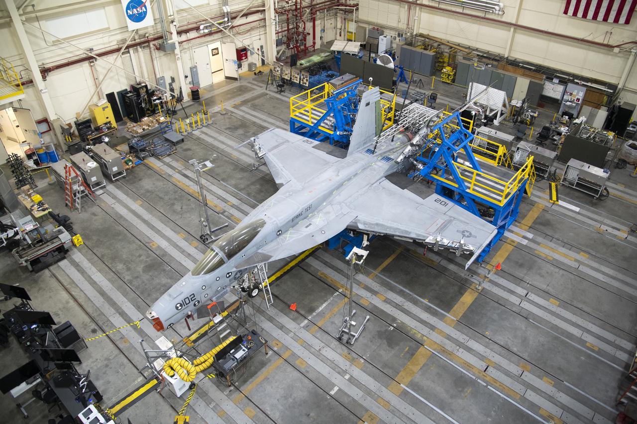 This view from above shows the vertical tail loads testing on a Navy F/A-18E that concluded in May, wrapping up the third phase of research at NASA’s Armstrong Flight Research Center in Edwards, California. The first two phases included loads calibration testing focused on the aircraft’s horizontal tails and wings. The aircraft is from the Naval Air Systems Command (NAVAIR) in Patuxent River, Maryland. NAVAIR retired its previous loads test aircraft and NASA Armstrong staff are assisting to prepare the new aircraft for its role to help safely manage flight maneuvers and determine how the F/A-18E fleet will perform if proposed upgrades are incorporated.
