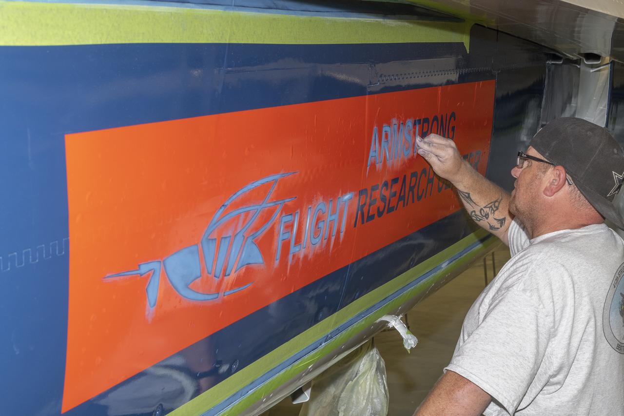John Bishop, who works at the U.S. Air Force Corrosion Control Facility, sands areas in a stencil for adding some finishing touches to NASA 862, which is an F/A-18D based at NASA’s Armstrong Flight Research Center in Edwards, California. The corrosion control facility is located on Edwards Air Force Base and is also known as the Paint Barn. 