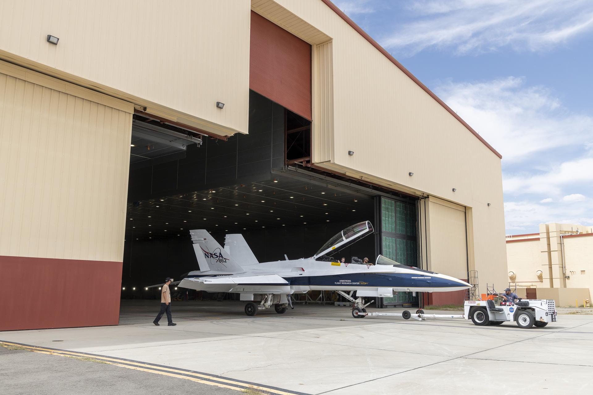 An aircraft is towed out of a hangar.