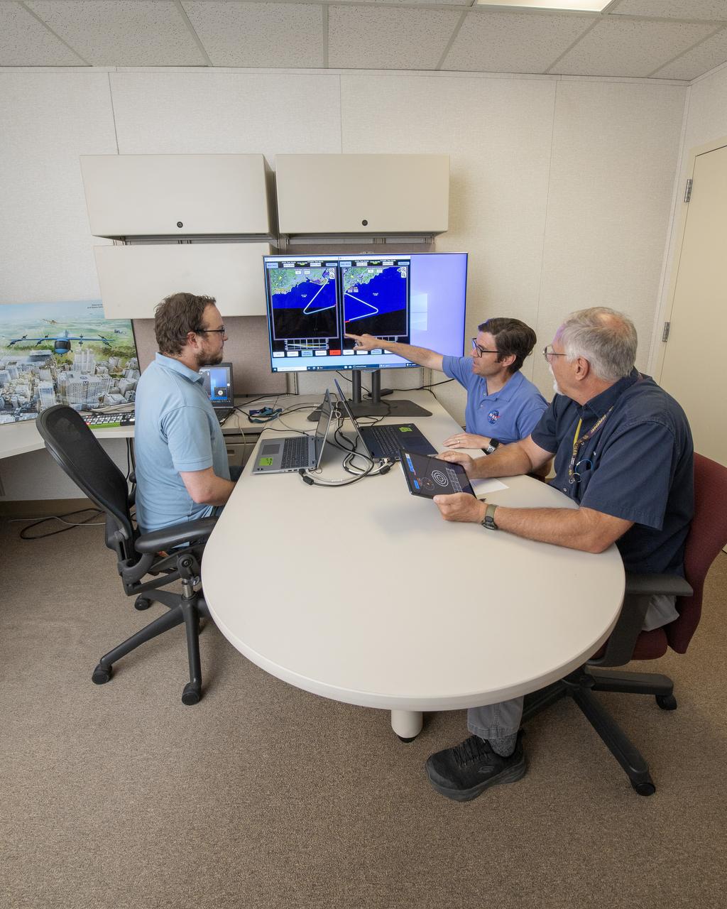NASA software developer, Ethan Williams, left, pilot Scott Howe, and operations test consultant Jan Scofield run a flight path management software simulation at NASA’s Armstrong Flight Research Center in Edwards, California in May 2023. This simulation research supports the integration of automated systems for the advanced air mobility mission.