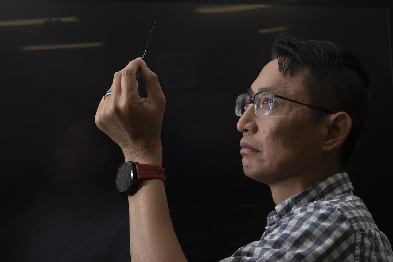 Patrick Chan, electronics engineer, and NASA Armstrong’s FOSS portfolio project manager, closely examines an optic fiber inside of a protective sleeve. Armstrong’s Fiber Optic Sensing System recently supported tests in which oxygen was turned into liquid oxygen at minus 297 degrees Fahrenheit. Testing was aimed at developing technologies could allow future astronauts to manufacture rocket fuel on the Moon.