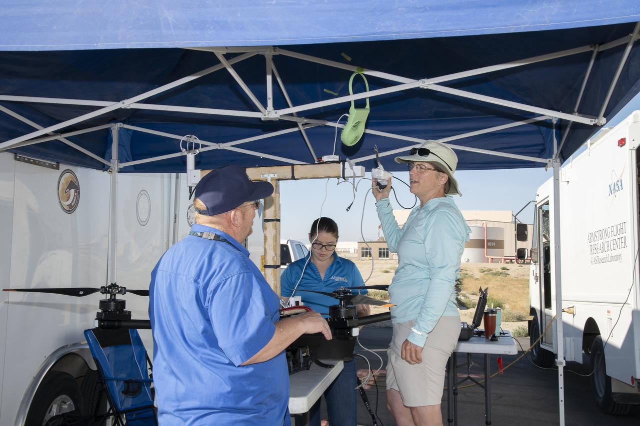 Jennifer Fowler talks to Red Jensen prior to a flight for the Advanced Exploration of Reliable Operation at Low Altitudes: Meteorology, Simulation and Technology campaign. Tyler Willhite completes some equipment checks for the research in the background. The weather study was at NASA’s Armstrong Flight Research Center in Edwards, California. The focus was to study wind from the ground to 2,000 feet to provide data to assist future drones to safely land on rooftop hubs called vertiports and to potentially improve weather prediction.