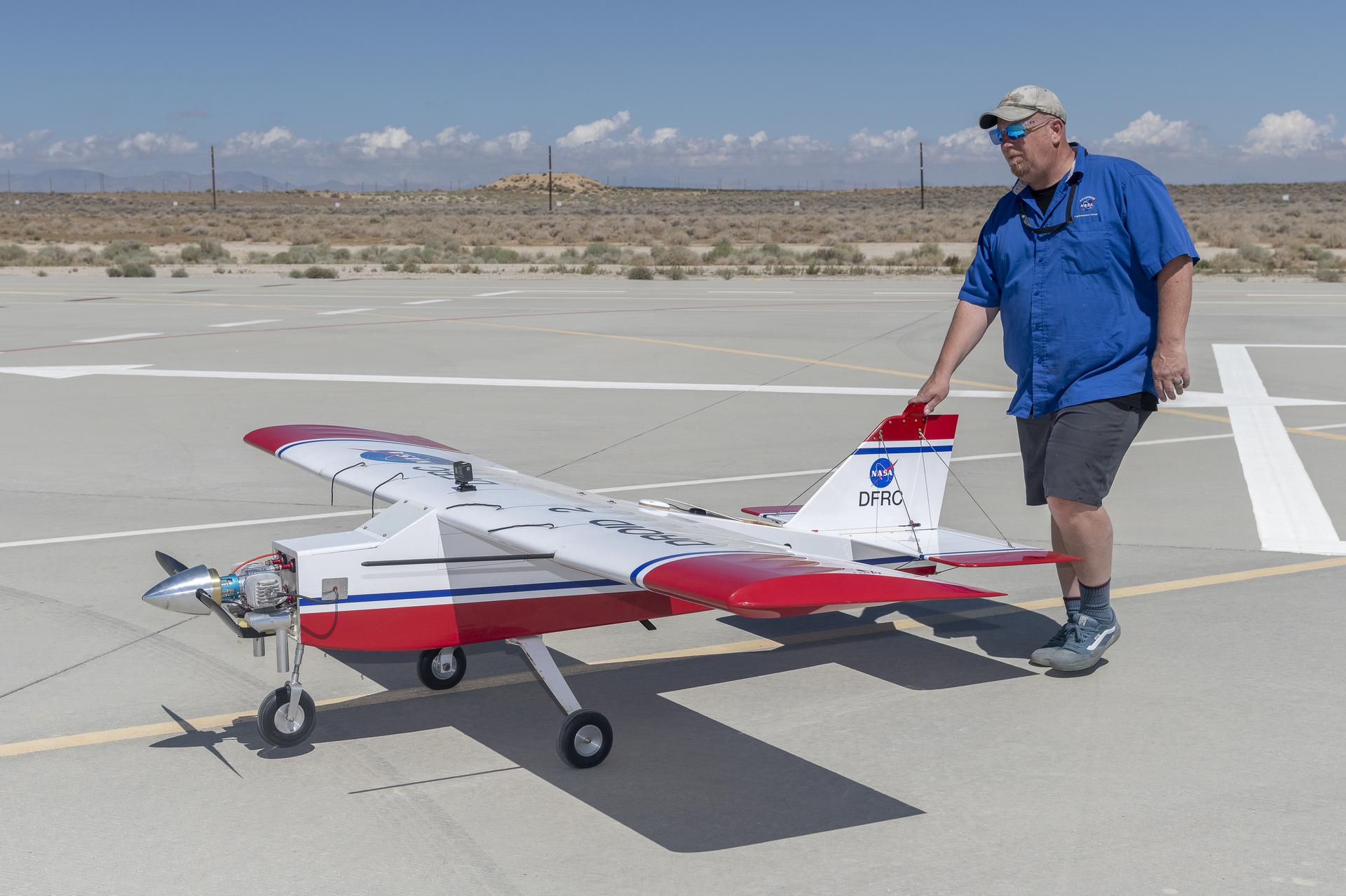 A man pushes a remotely piloted drone into position to take off.