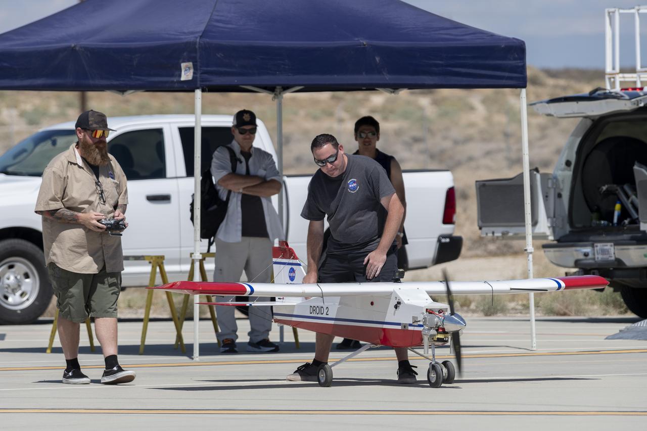 Justin Hall, left, prepares to pilot the DROID 2 (Dryden Remotely Operated Integrated Drone 2) aircraft, as John Melton watches and Justin Link makes a final adjustment. The flight was part of the Advanced Exploration of Reliable Operation at Low Altitudes: Meteorology, Simulation, and Technology campaign. The weather study was at NASA's Armstrong Flight Research Center in Edwards, California. The focus was to study wind to provide data for safe takeoff and landing of future air taxis.