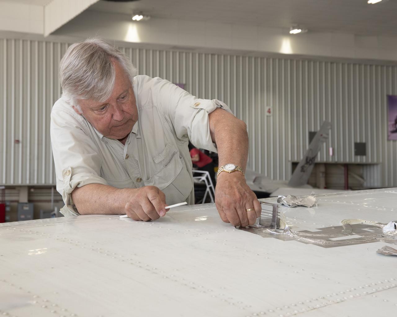 Cal Poly San Luis Obispo Professor Russ Westphal works on the Boundary Layer Data System (BLDS) attached to the wing of a Beechcraft Beech 200 Super King Air aircraft. The BLDS was attached to the aircraft with removable adhesives for a flight test at NASA’s Armstrong Flight Research Center.