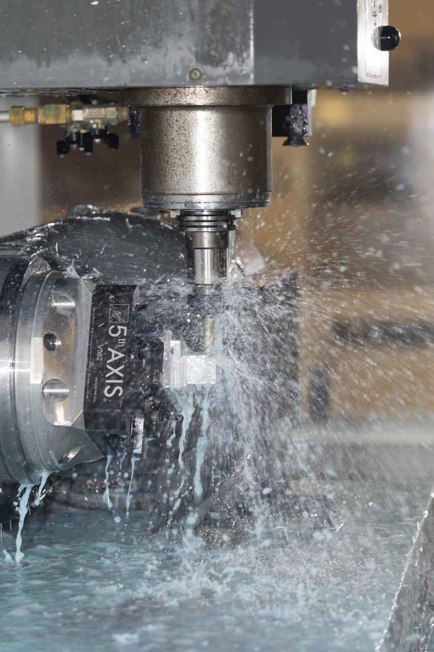 A machine cuts, rotates, and turns a block of aluminum to make a forward wing strut fastener for a 10-foot model of the Transonic Truss-Braced Wing at NASA’s Armstrong Flight Research Center, in Edwards, California. The aircraft concept involves a wing braced on an aircraft using diagonal struts that also add lift and could result in significantly improved aerodynamics.
