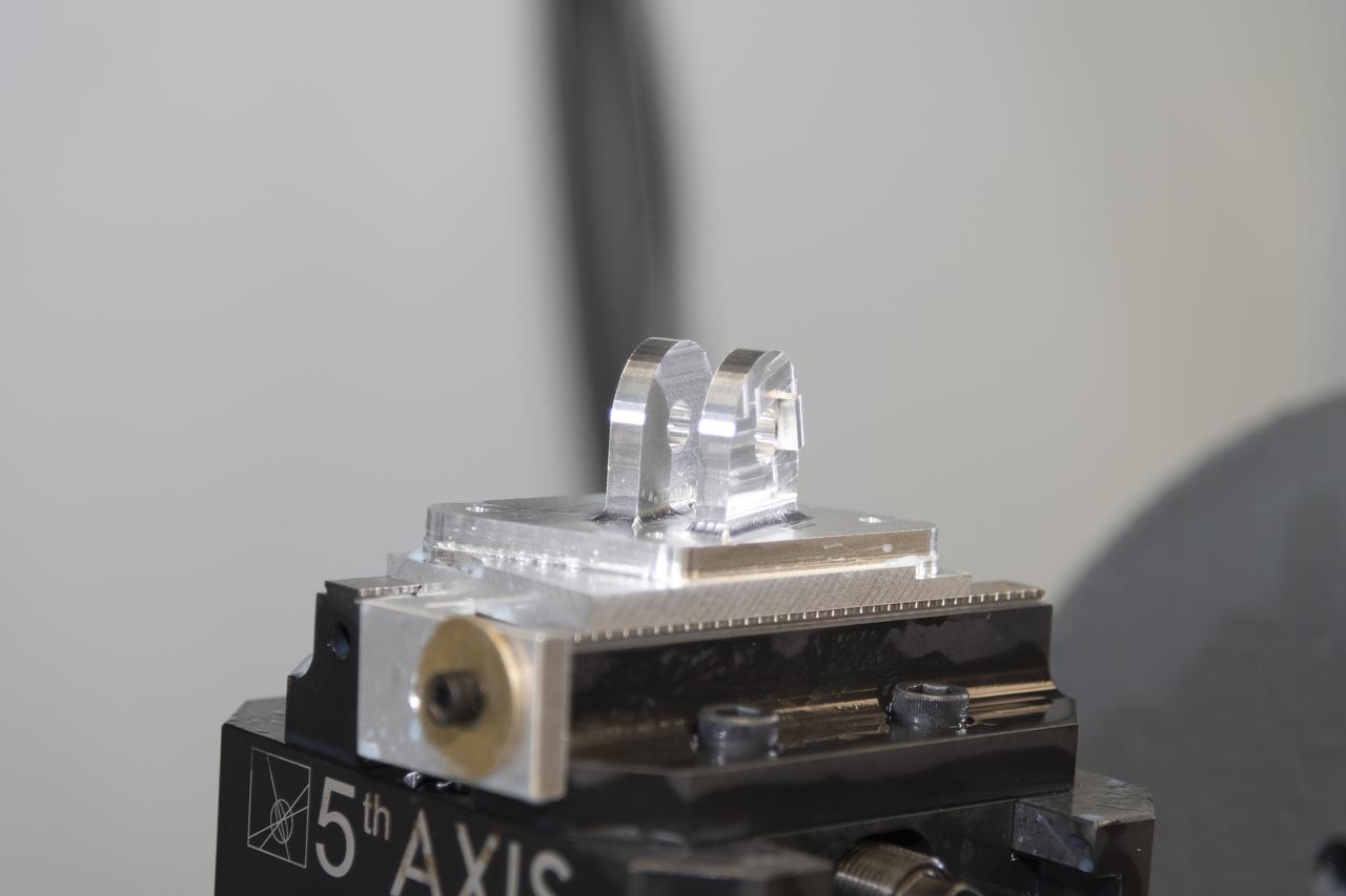 A block of aluminum is transformed by a machine programmed to cut, rotate, and turn it to make a forward wing strut fastener for a 10-foot model of the Transonic Truss-Braced Wing at NASA’s Armstrong Flight Research Center, in Edwards, California. The aircraft concept involves a wing braced on an aircraft using diagonal struts that also add lift and could result in significantly improved aerodynamics.