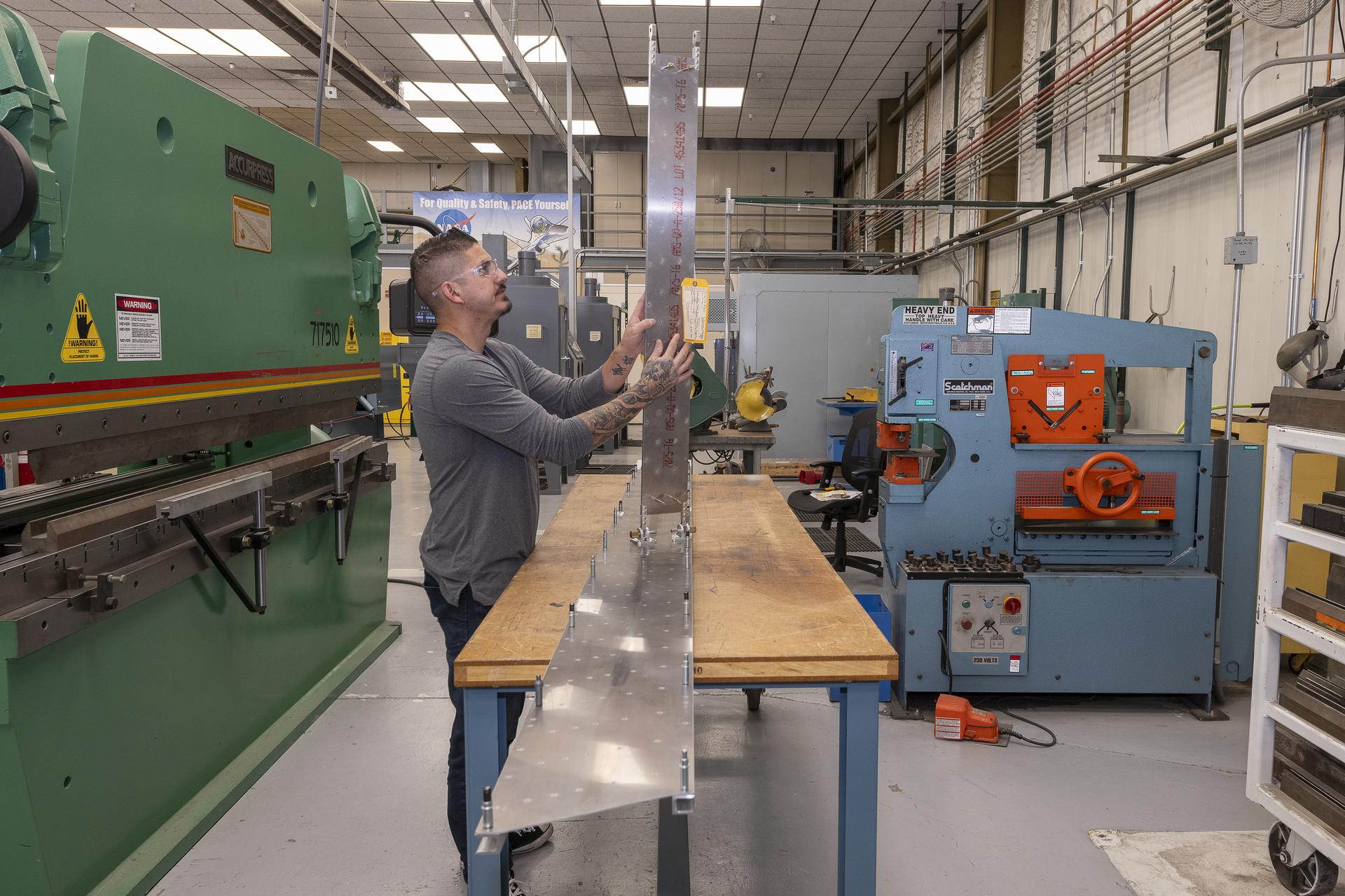 A man attaches components to assure they will fit together for testing of a 10-foot wing model.