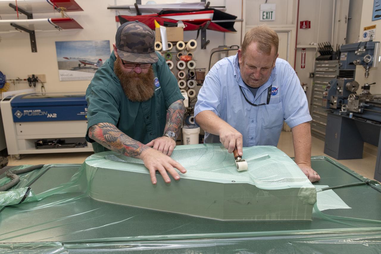 Justin Hall, left, and Robert “Red” Jensen work to eliminate the air around an aircraft mold where it will cure for eight hours. The subscale aircraft development at NASA’s Armstrong Flight Research Center in Edwards, California, may result in an atmospheric probe.