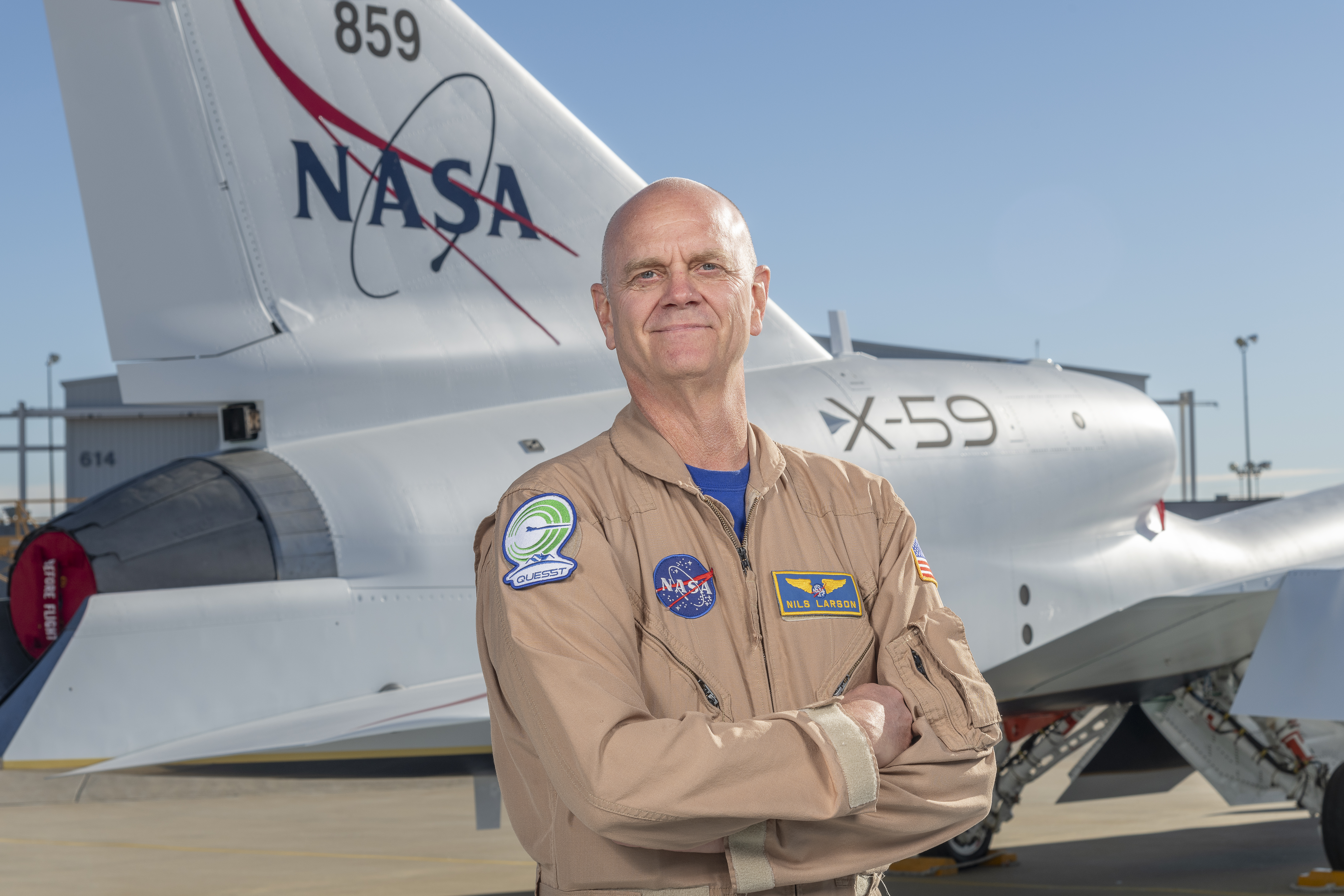 NASA test pilot Nils Larson poses with the newly-painted X-59 as it sits on the ramp at Lockheed Martin Skunk Works in Palmdale, California. The X-59 is the centerpiece of NASA’s Quesst mission, which seeks to solve one of the major barriers to supersonic flight over land, currently banned in the United States, by making sonic booms quieter.