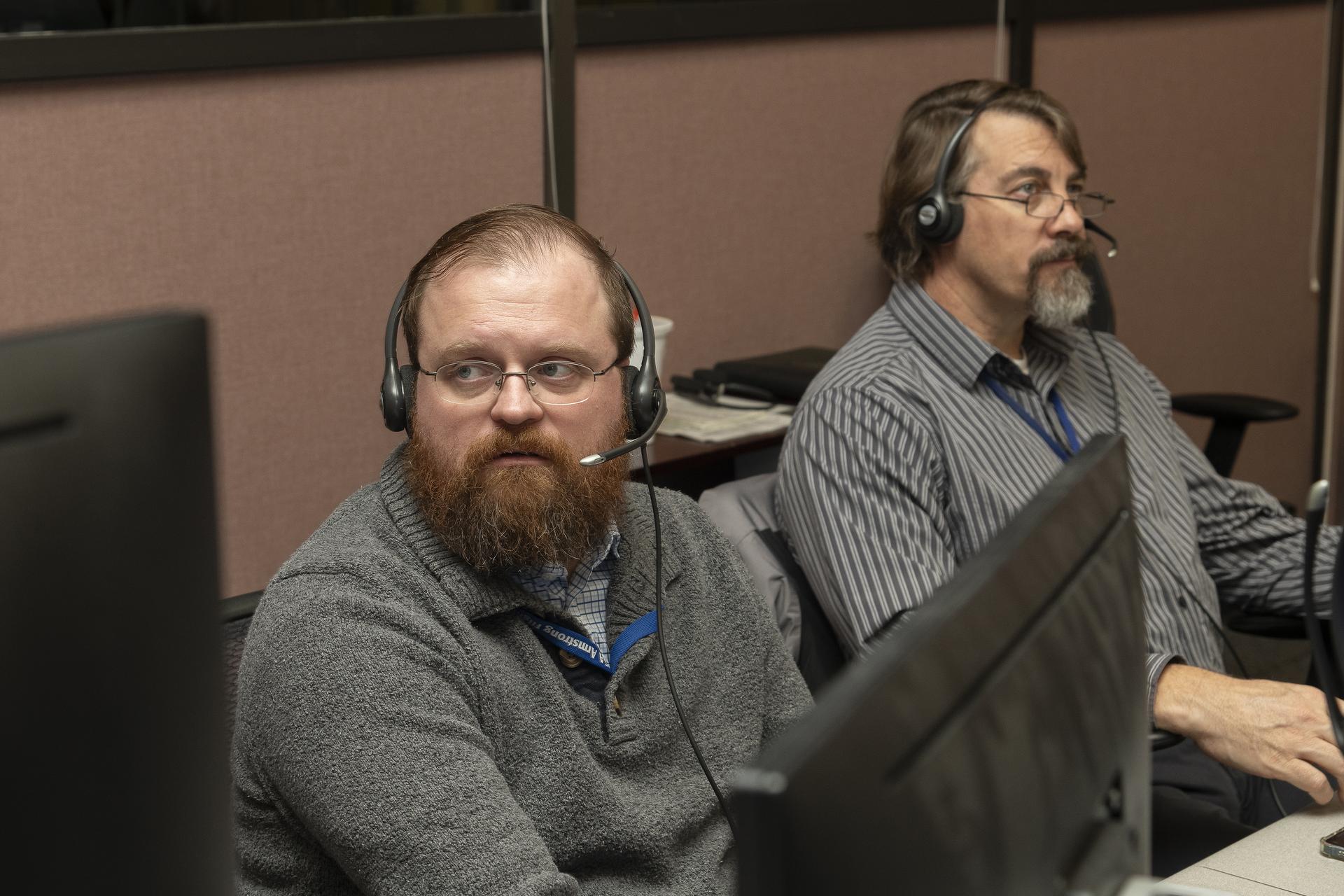 Two men monitor a flight in a NASA control room.