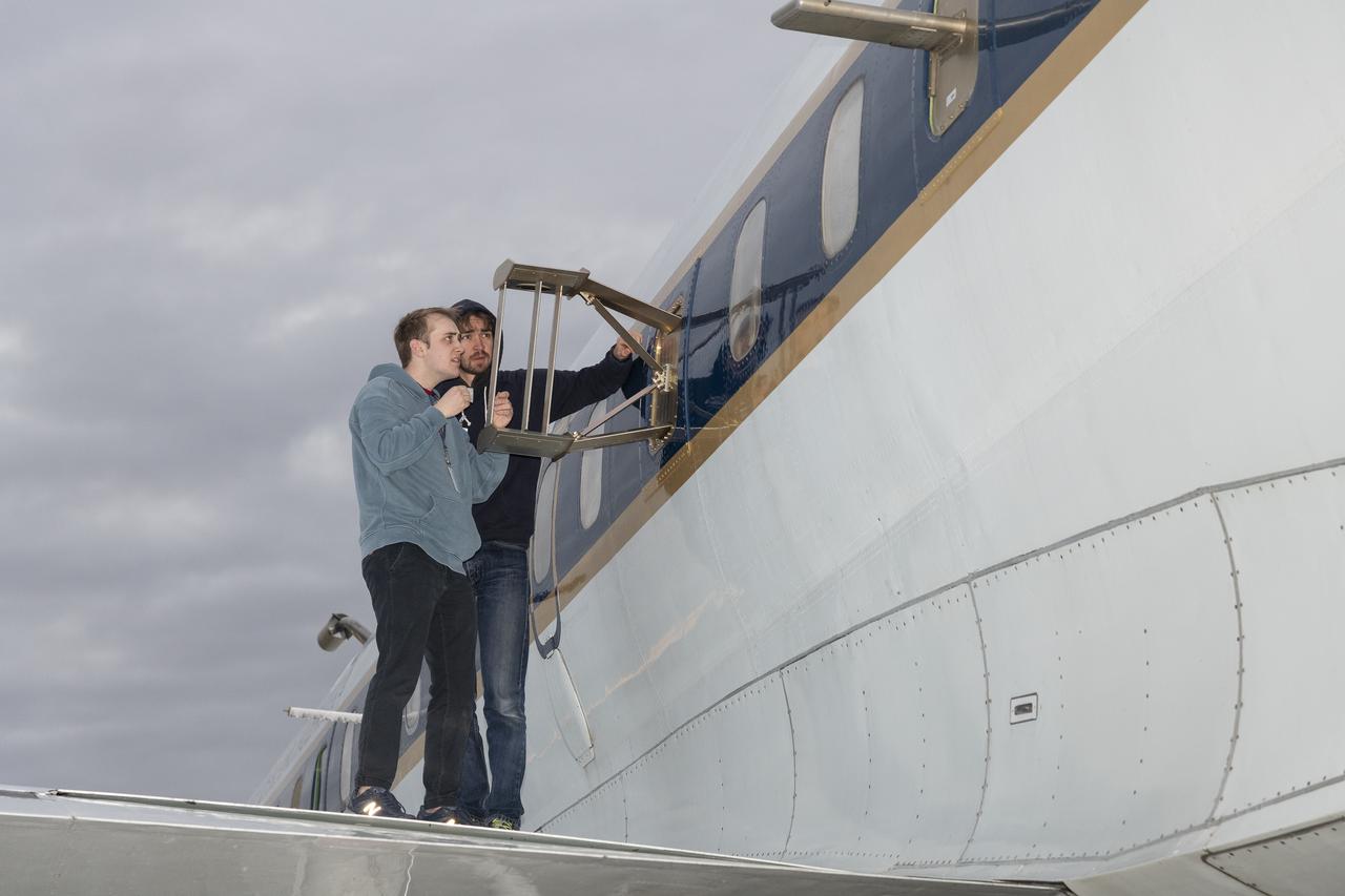 Scientists Ryan Boyd (left) and Vladislav Sevostianov (right) attend to the Optical Payload for Lasercomm Science (OPALS) instrument on the exterior the DC-8 aircraft at Building 703 in Palmdale, CA. The DC-8 aircraft is prepared for its last mission, ASIA-AQ (Airborne and Satellite Investigation of Asian Air Quality), that will collect detailed air quality data over several locations in Asia to improve the understanding of local air quality in collaboration with local scientists, air quality agencies, and government partners