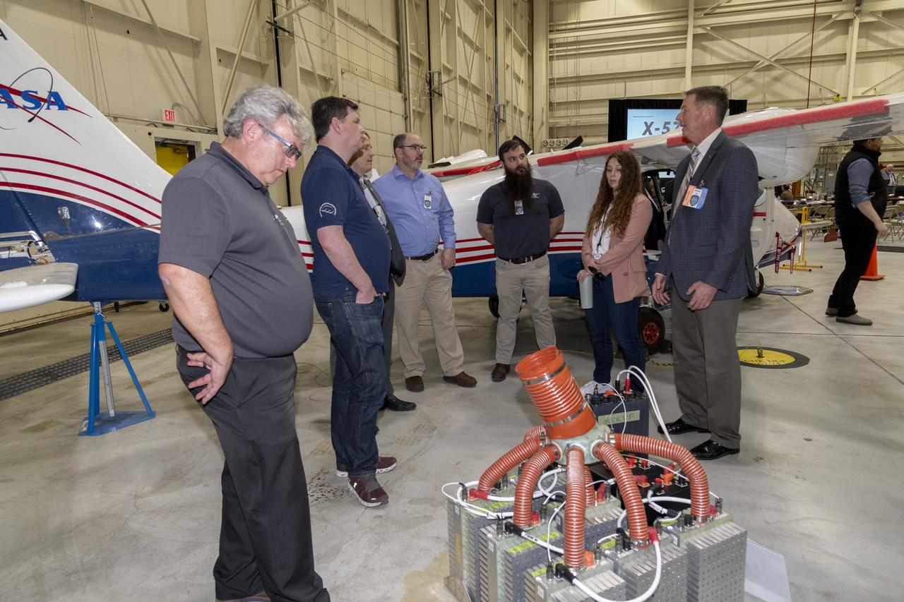 Attendees gather next to the X-57 Maxwell aircraft during a knowledge sharing meeting at NASA’s Armstrong Flight Research Center in Edwards, California looking at a display of the battery assembly that normally sits inside the aircraft.