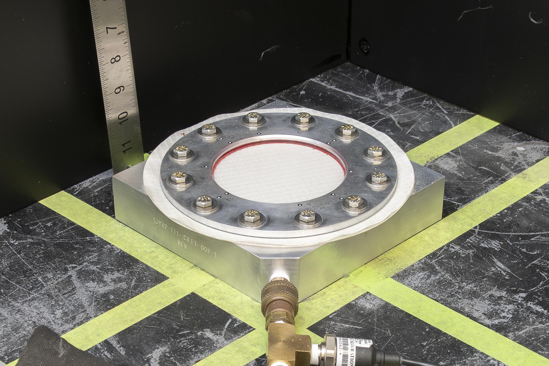 Fabric is secured in a round test fixture where pressure will soon be applied.
