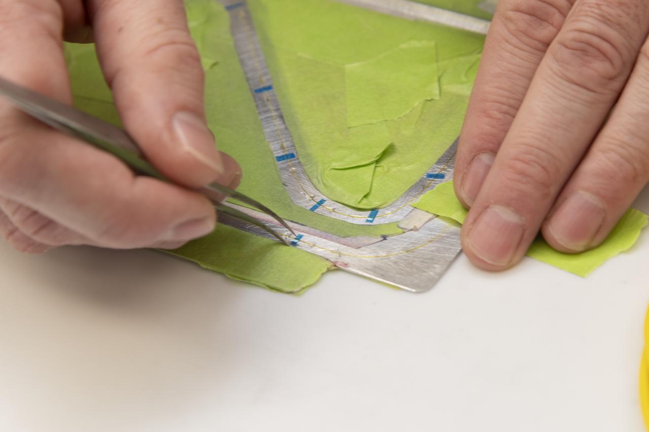 Engineering technician Jeff Howell removes thin pieces of tape from fiber used for a bonding process on the Mock Truss-Braced Wing 10-foot model at NASA’s Armstrong Flight Research Center in Edwards, California.