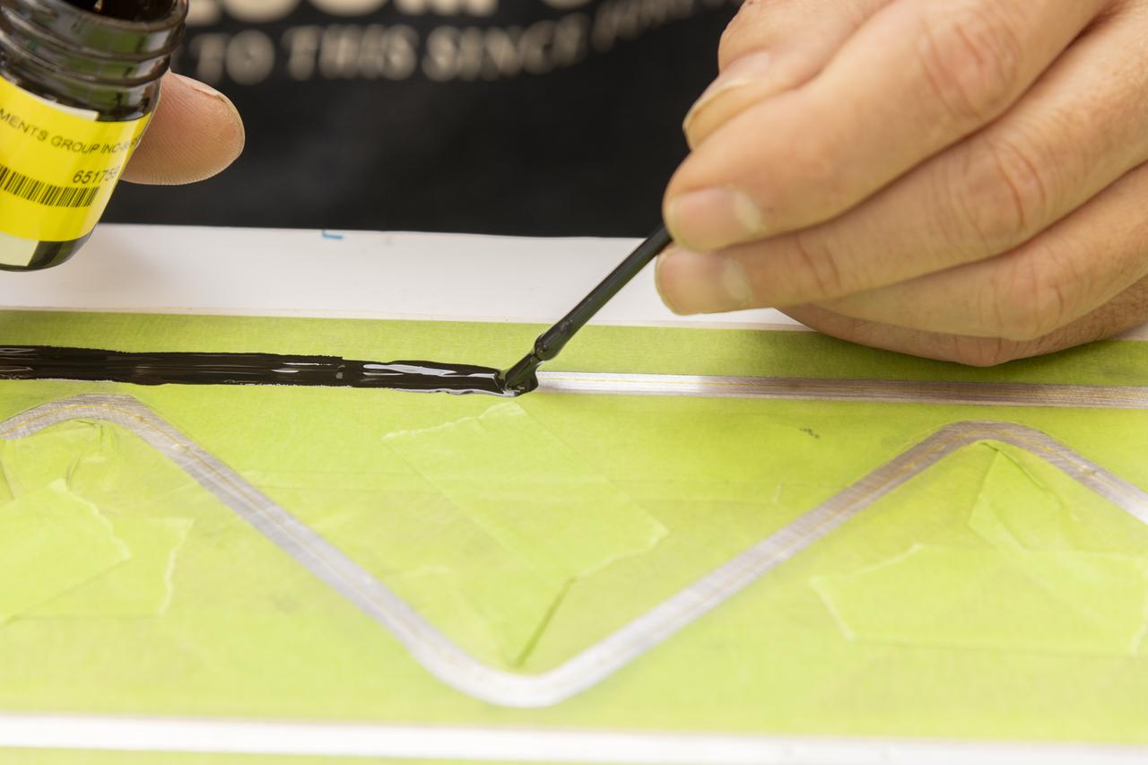An epoxy is applied to adhere the fiber optic sensor installation on the Mock Truss-Braced Wing 10-foot model at NASA’s Armstrong Flight Research Center in Edwards, California.