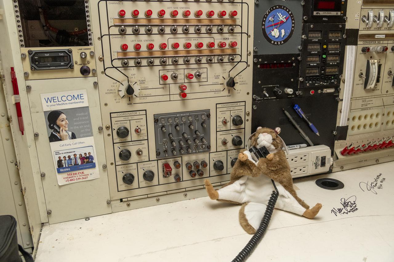 Orville, NASA’s high-flying squirrel, uses the microphone at the mission director station onboard the DC-8 aircraft at NASA’s Armstrong Flight Research Center Building 703 in Palmdale, California. On May 2, 2024, NASA personnel, friends, and family celebrated the DC-8 staff, aircraft, and science campaigns.