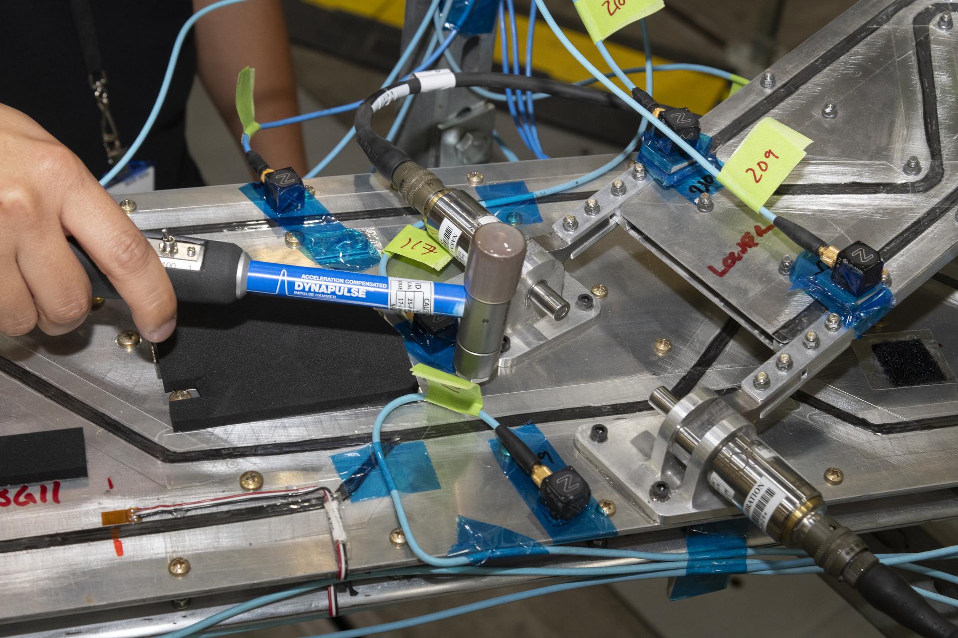 A wing test article is tapped with an instrumented hammer.