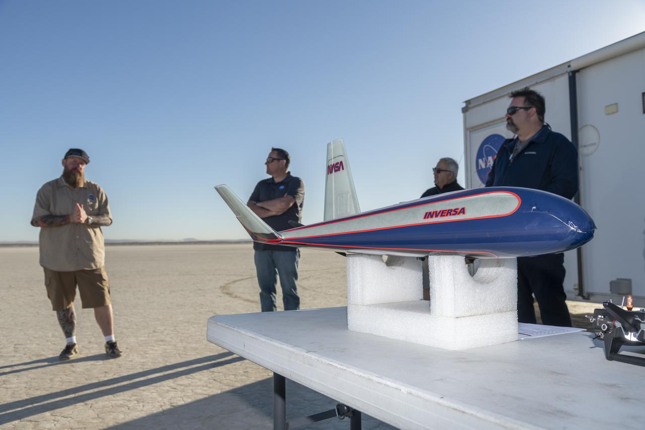 The atmospheric probe model on a stand is prepped for flight and release from a quad rotor remotely piloted aircraft. The probe successfully flew on Oct. 22, 2024, above Rogers Dry Lake, a flight area adjacent to NASA’s Armstrong Flight Research Center in Edwards, California. The probe was designed and built at the center. In the background from left are Justin Hall, chief pilot of small, unmanned aircraft systems; Justin Link, small unmanned aircraft systems pilot; communications writer Jay Levine; and John Bodylski, atmospheric probe principal investigator.