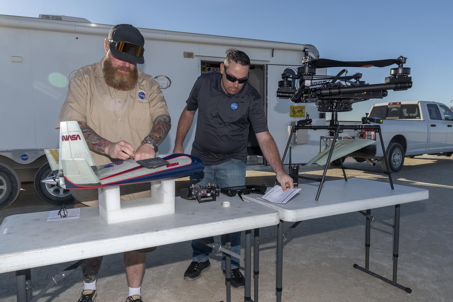 Two men prepare an atmospheric probe model for flight.