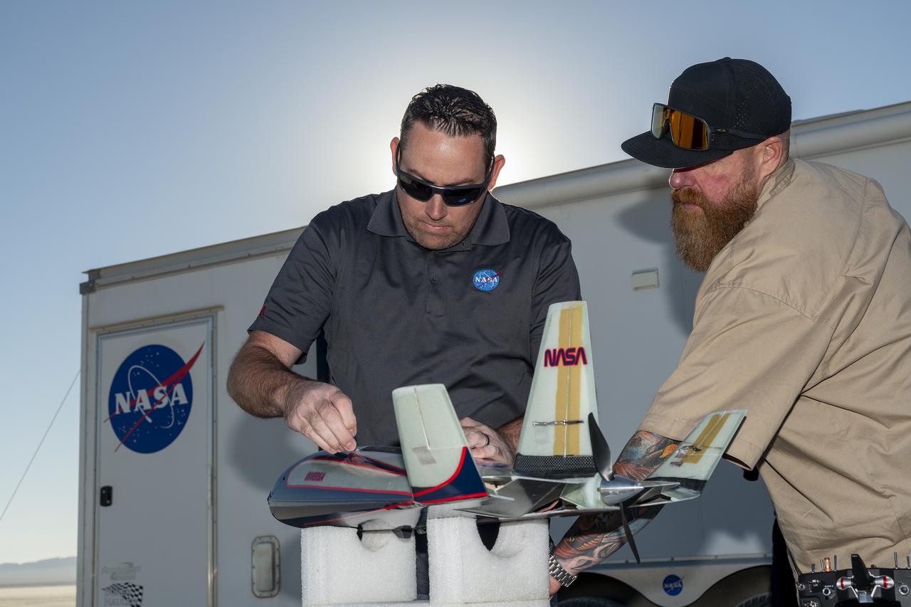 Justin Link, left, small unmanned aircraft systems pilot, and Justin Hall, chief pilot of small unmanned aircraft systems, prepare an atmospheric probe model for flight on Oct. 22, 2024. A quad rotor remotely piloted aircraft released the probe above Rogers Dry Lake, a flight area adjacent NASA’s Armstrong Flight Research Center in Edwards, California. The probe was designed and built at the center.