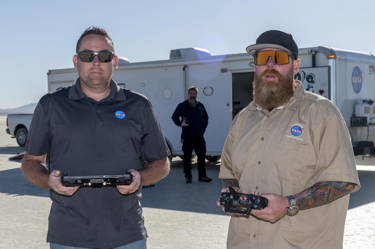 Justin Link, left, unmanned aircraft systems pilot, and Justin Hall, chief pilot for small unmanned aircraft systems, prepare to fly a quad rotor remotely piloted aircraft and an atmospheric probe model on Oct. 22, 2024. John Bodylski, probe principal investigator, watches the preparation for flight. The quad rotor aircraft released the probe above Rogers Dry Lake, a flight area adjacent NASA’s Armstrong Flight Research Center in Edwards, California. The probe was designed and built at the center.