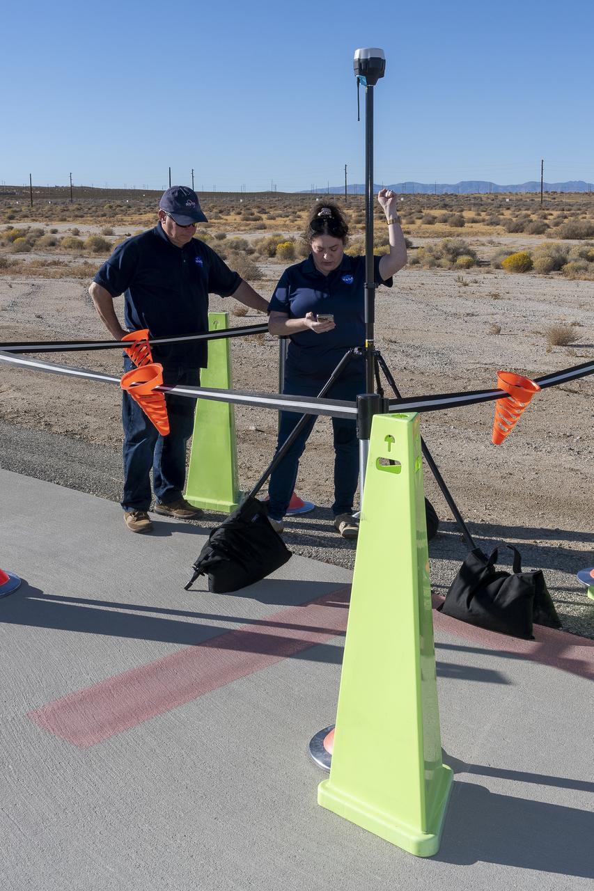 NASA Pathways intern Saré Culbertson, right, works with NASA operations engineer Jack Hayes at NASA’s Armstrong Flight Research Center in Edwards, California, on Nov. 7, 2024. They are verifying GPS and global navigation satellite system coordinates using Emlid Reach RS2+ receiver equipment, which supports surveying, mapping, and navigation in preparation for future air taxi test flight research.