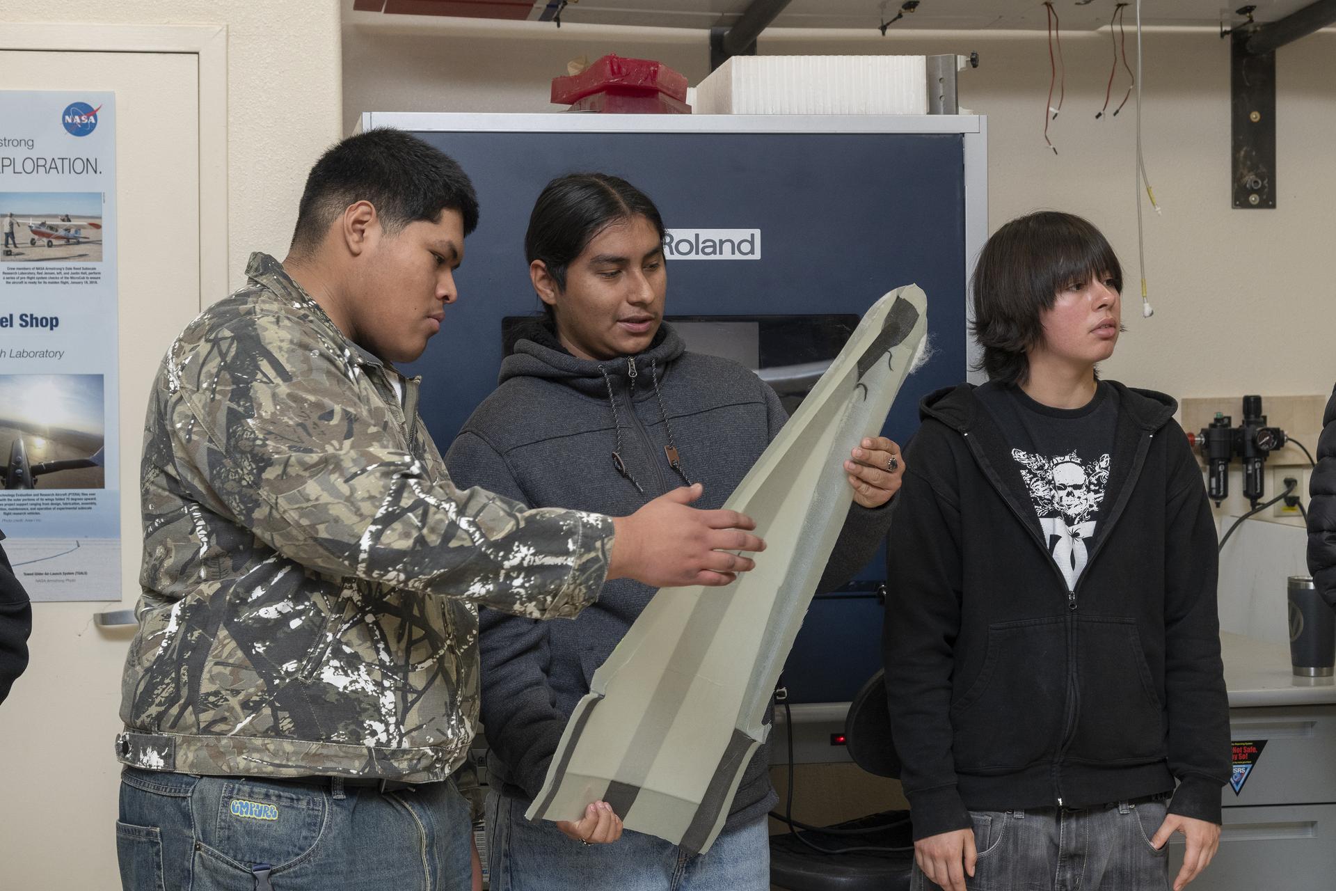 Students look at a subscale aircraft in a research lab.