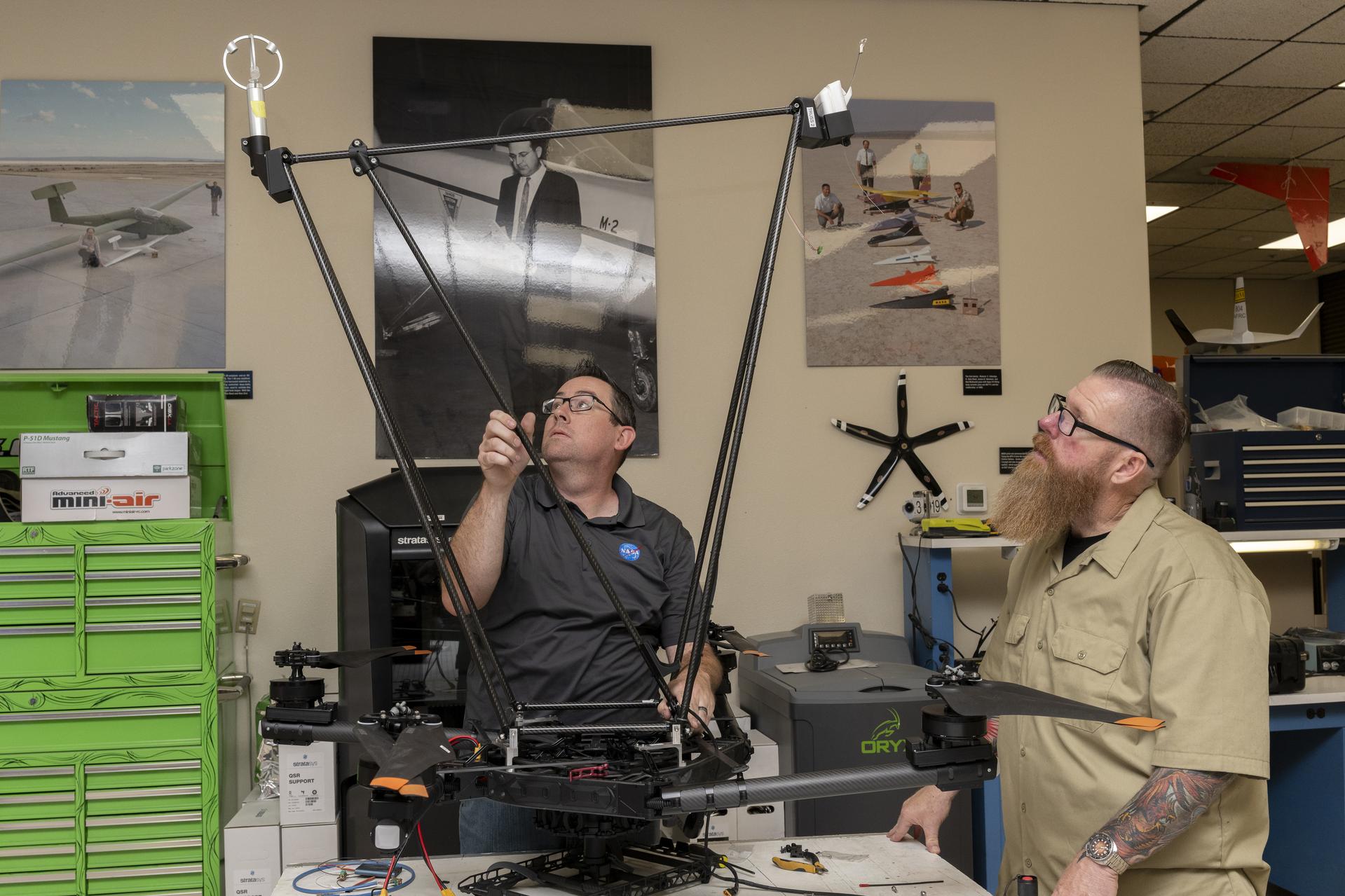 Two men integrate instruments onto a drone.