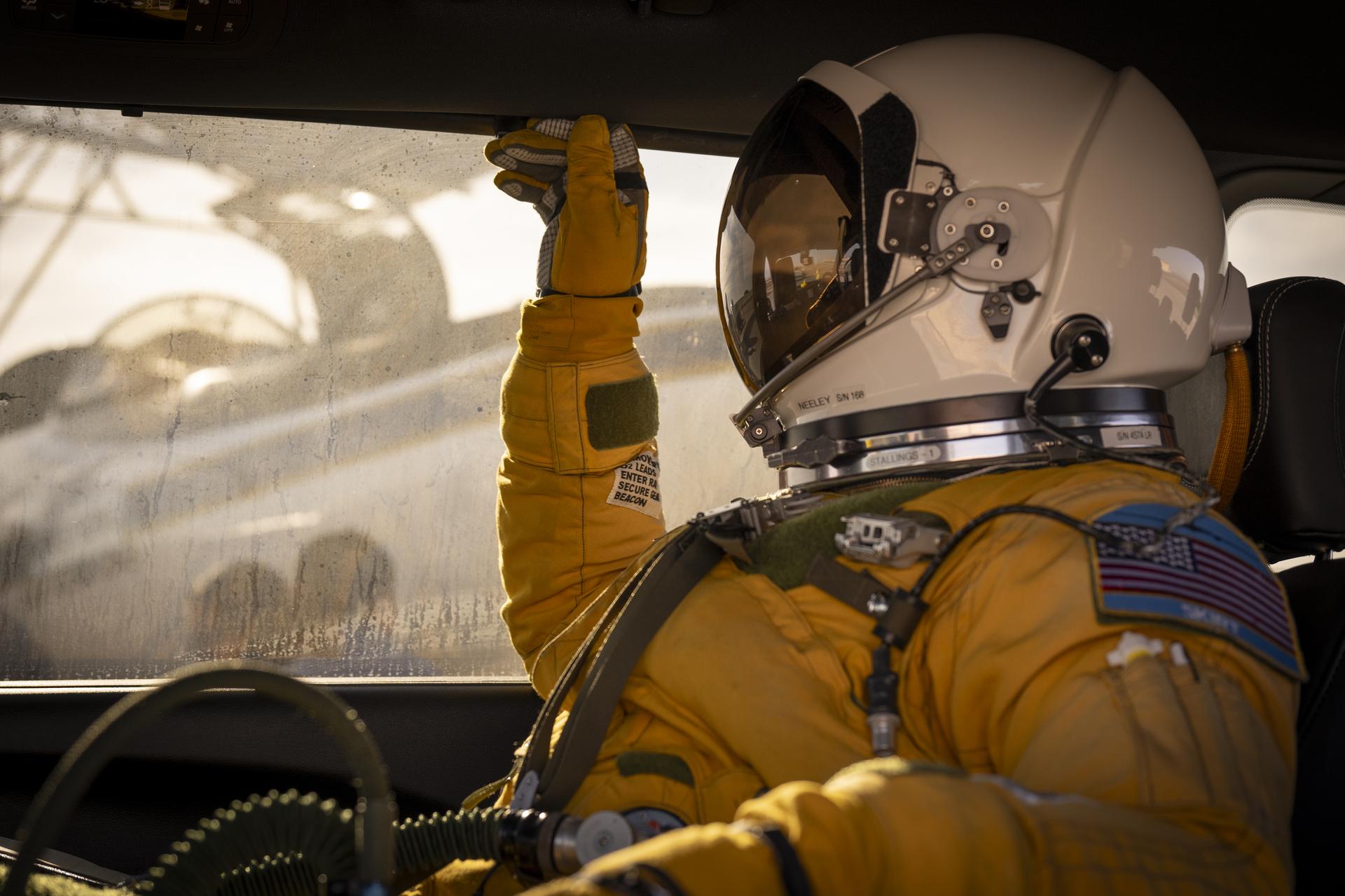A pilot in a full pressure suit sits inside a vehicle, with his hand resting on the interior ceiling before a NASA ER-2 flight at Armstrong Flight Research Center.