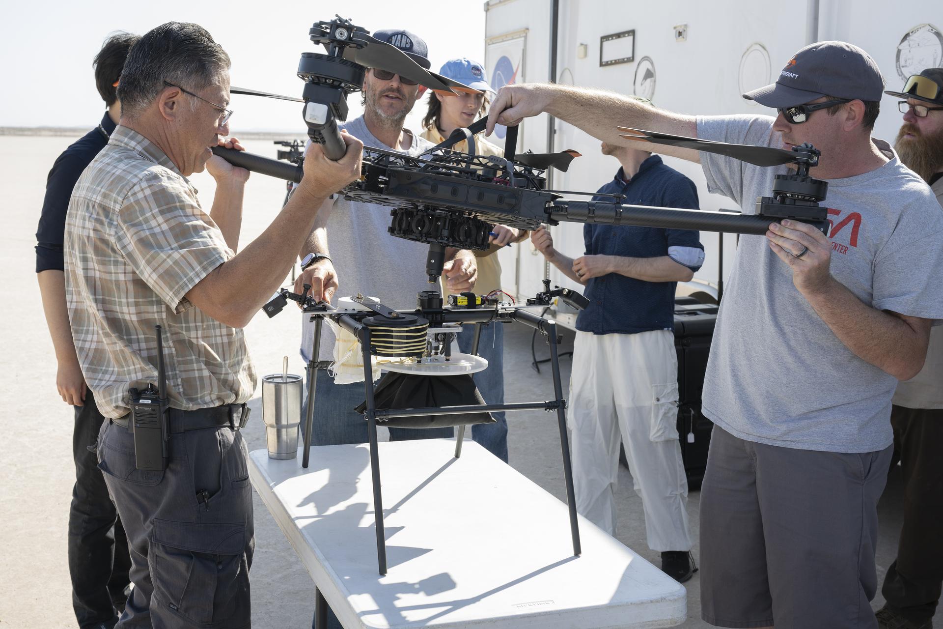 Two men attached a science experiment to a drone for a research flight.
