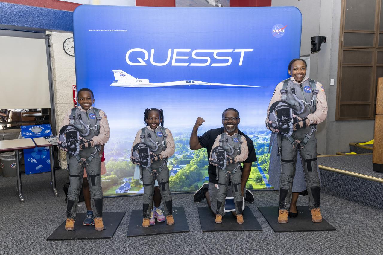 During Bring Kids to Work Day at NASA’s Armstrong Flight Research Center in Edwards, California, on June 17, 2025, participants pose with flight suit cutouts in front of NASA’s Quesst display. NASA's Quesst mission, which features the agency’s X-59 quiet supersonic experimental aircraft, will demonstrate technology to fly supersonic, or faster than the speed of sound, without generating loud sonic booms.