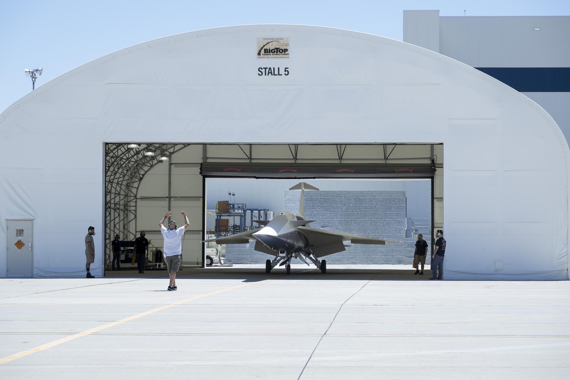 ASA's X-59 aircraft exits a large white hangar labeled 