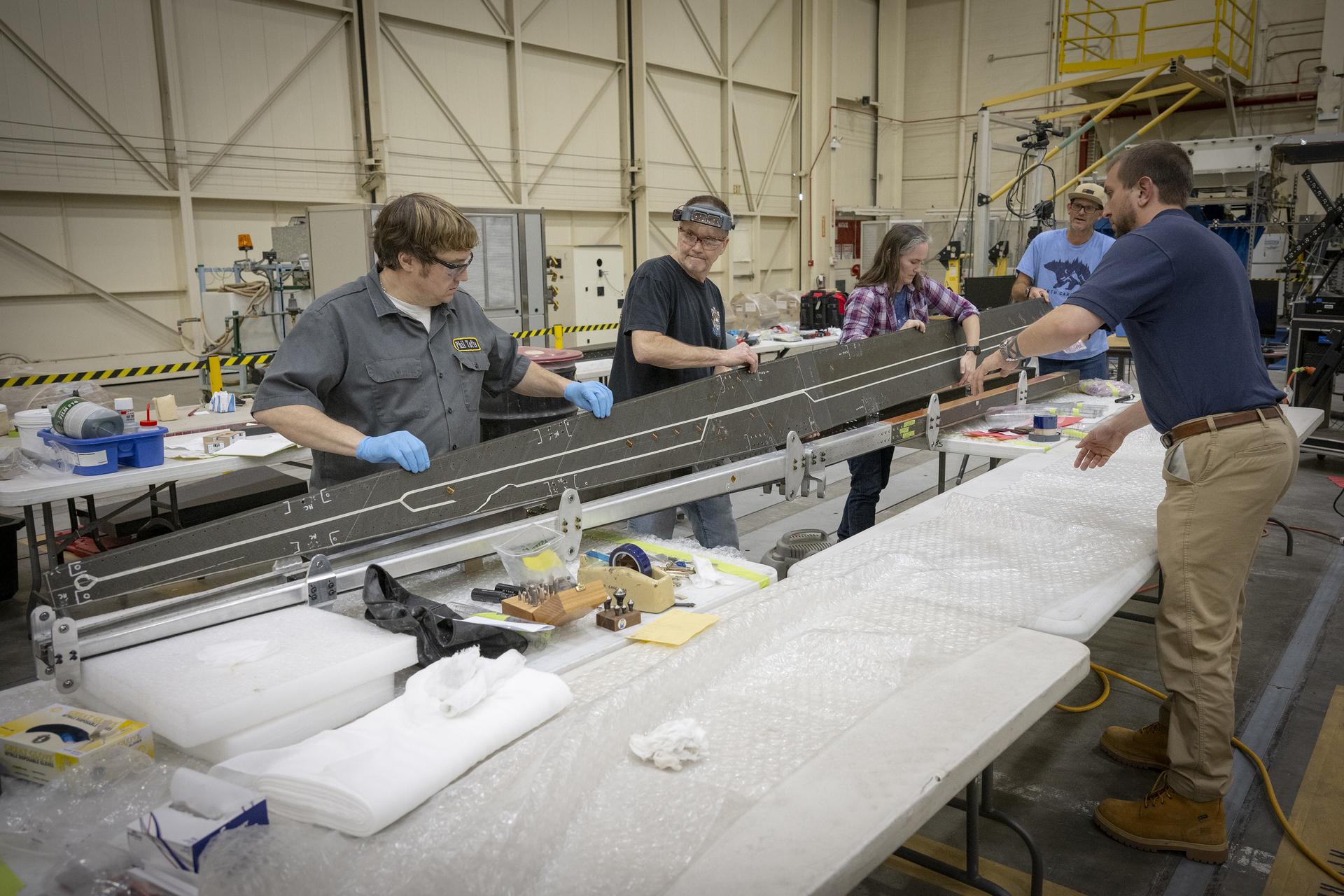 Lab technicians Phil Tofts, Chris McLain, and Jeff Howell and NASA engineers Erin Anderson and Richard Larson prepare the 15-foot Structural Wing Experiment Evaluating Truss-bracing model in the Flight Loads Laboratory at NASA’s Armstrong Flight Research Center in Edwards, California, on Thursday, Dec. 11, 2025. The model is part of NASA’s research to develop technologies for future ultra-efficient aircraft.
