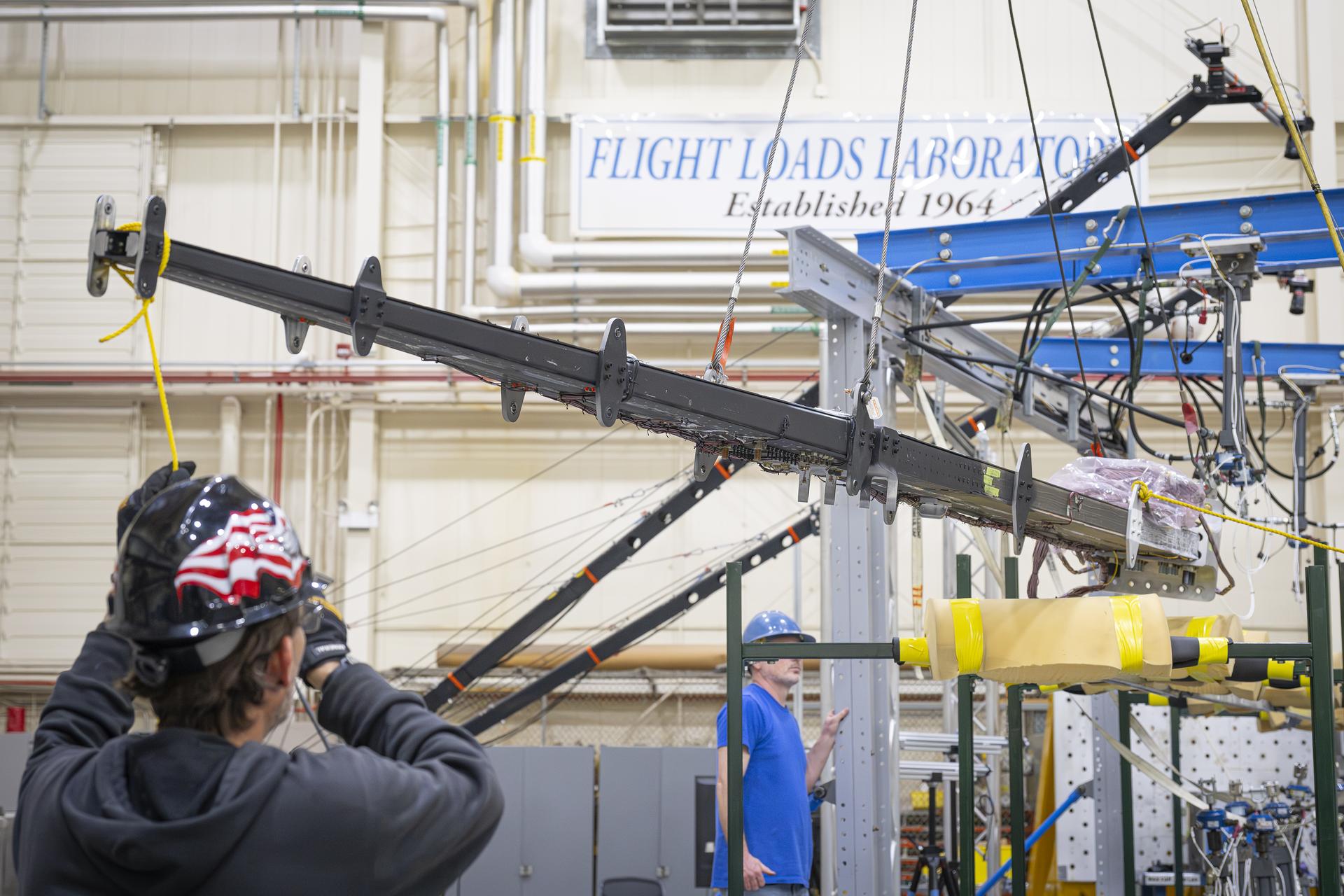 Lab technicians Jeff Howell, left and Chris Mount install the 15-foot Structural Wing Experiment Evaluating Truss-bracing model in the Flight Loads Lab at NASA’s Armstrong Flight Research Center in Edwards, California, Wednesday, February 11, 2026. The model is part of NASA’s research to develop technologies for future ultra-efficient aircraft.