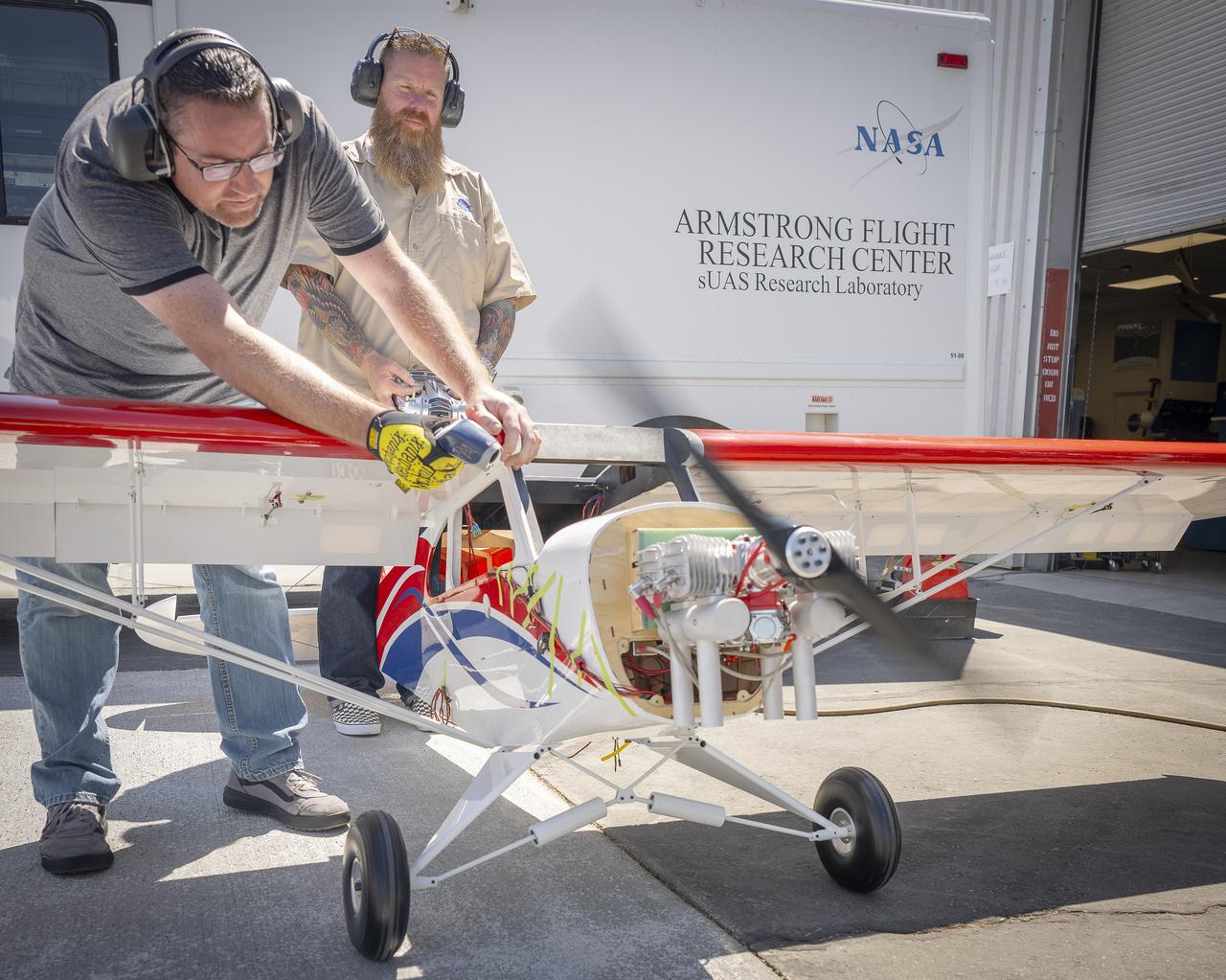 Justin Link, left, holds the subscale aircraft in place, while Justin Hall manages engine speed during preliminary engine tests on Friday, Sept. 12, 2025, at NASA’s Armstong Flight Research Center in Edwards, California. Link is a pilot for small uncrewed aircraft systems at the center’s Dale Reed Subscale Flight Research Laboratory and Hall is the chief pilot.