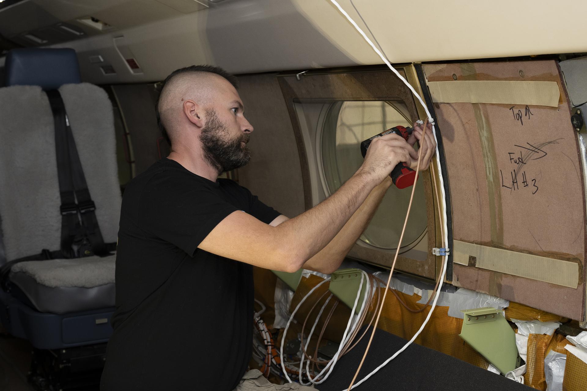Kelly Jellison, an avionics lead, installs a clip to secure wiring installed on a NASA Gulfstream G-III aircraft on Wednesday, Jan. 7, 2026, at NASA’s Armstrong Flight Research Center in Edwards, California. The modifications prepare the aircraft to join three others flying at different altitudes to capture a complete view of the Orion spacecraft’s heat shield during Artemis II reentry. This effort is part of NASA’s Scientifically Calibrated In-Flight Imagery project.