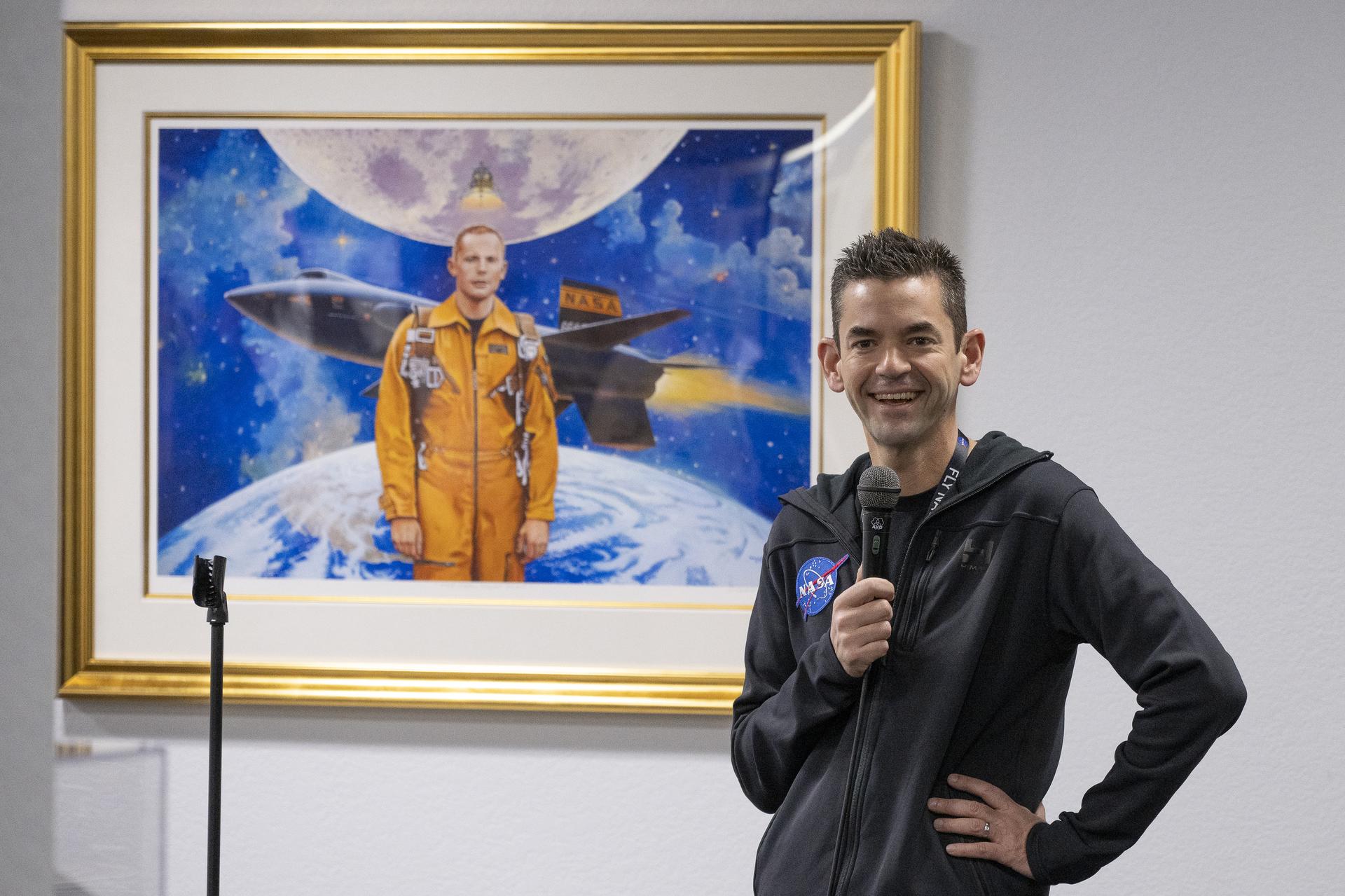 NASA Administrator Jared Isaacman speaks with employees and contractors in front of a painting of former astronaut and research pilot Neil Armstrong during Isaacman’s visit to NASA’s Armstrong Flight Research Center in Edwards, California, on Sunday, Jan. 25, 2026. Isaacman, NASA’s 15th administrator, began visiting the agency’s centers after his appointment on Dec. 17, 2025.