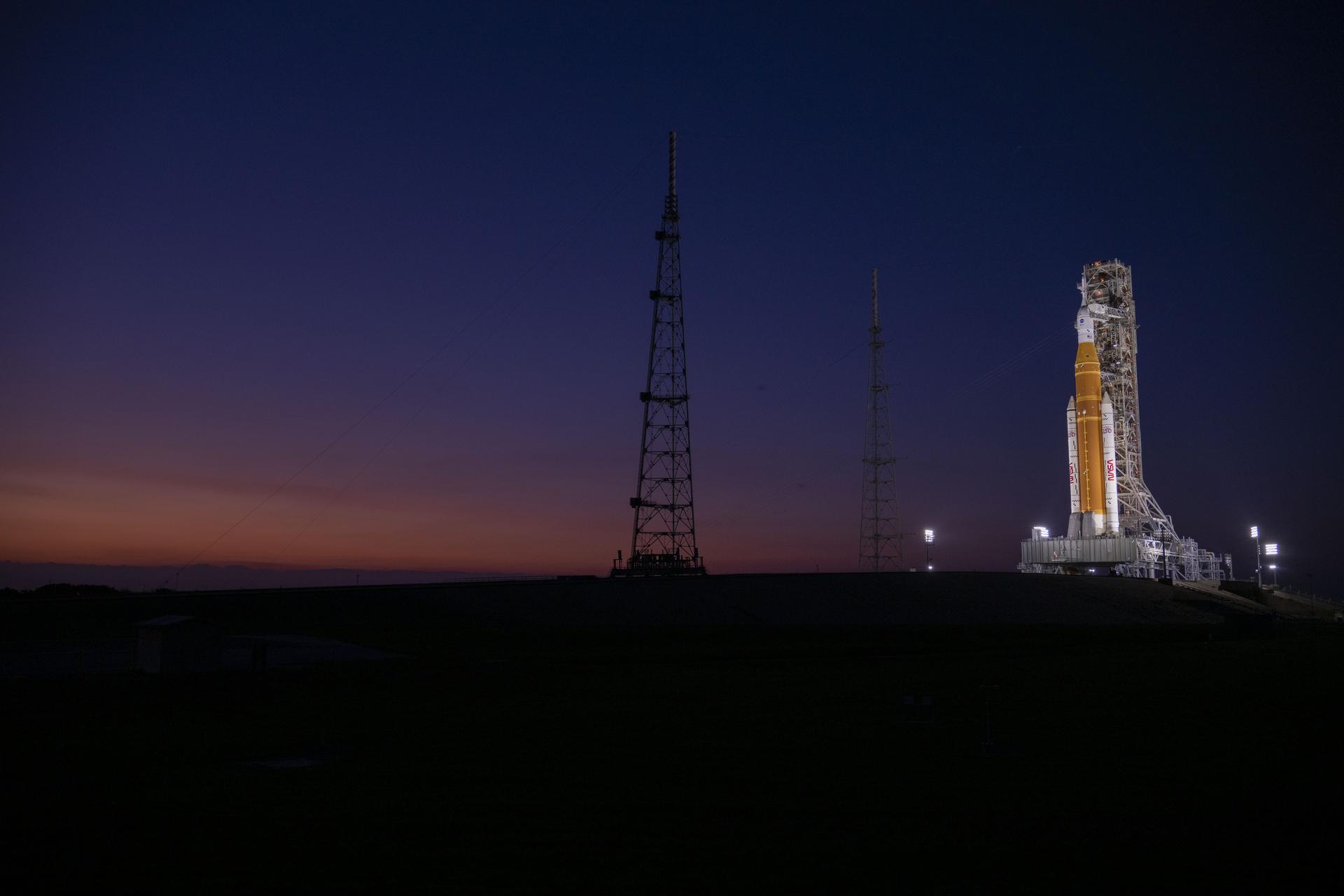 The Sun sets behind NASA’s Artemis II SLS (Space Launch System) rocket and Orion spacecraft atop a mobile launcher at Launch Complex 39B at NASA’s Kennedy Space Center in Florida on Friday, March 27, 2026. The Artemis II test flight will take Commander Reid Wiseman, Pilot Victor Glover, and Mission Specialist Christina Koch from NASA, and Mission Specialist Jeremy Hansen from the CSA (Canadian Space Agency), around the Moon and back to Earth.