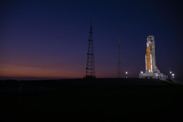 The Sun sets behind NASA’s Artemis II SLS (Space Launch System) rocket and Or...