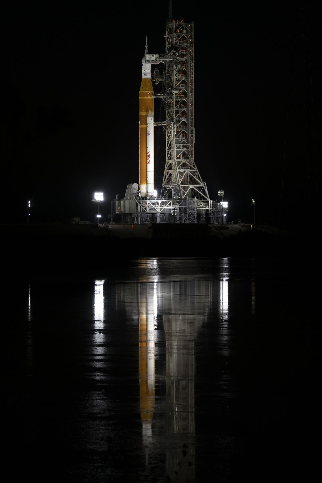 Spotlights illuminate NASA’s SLS (Space Launch System) rocket with the Orion spacecraft atop a mobile launcher at Launch Complex 39B at NASA’s Kennedy Space Center in Florida on Friday, March 27,  2026. The Artemis II test flight will take Commander Reid Wiseman, Pilot Victor Glover, and Mission Specialist Christina Koch from NASA, and Mission Specialist Jeremy Hansen from the CSA (Canadian Space Agency), around the Moon and back to Earth.