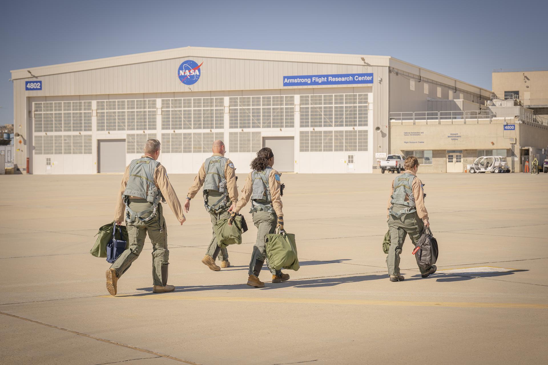 Four NASA employees walk toward a hangar after a flight Thursday, Feb. 4, 2026, at NASA’s Armstrong Flight Research Center in Edwards, California. The team supports the agency’s Crossflow Attenuated Natural Laminar Flow (CATNLF) project, which aims to lower fuel costs for future commercial aircraft by testing a scale-model wing designed to improve laminar flow.