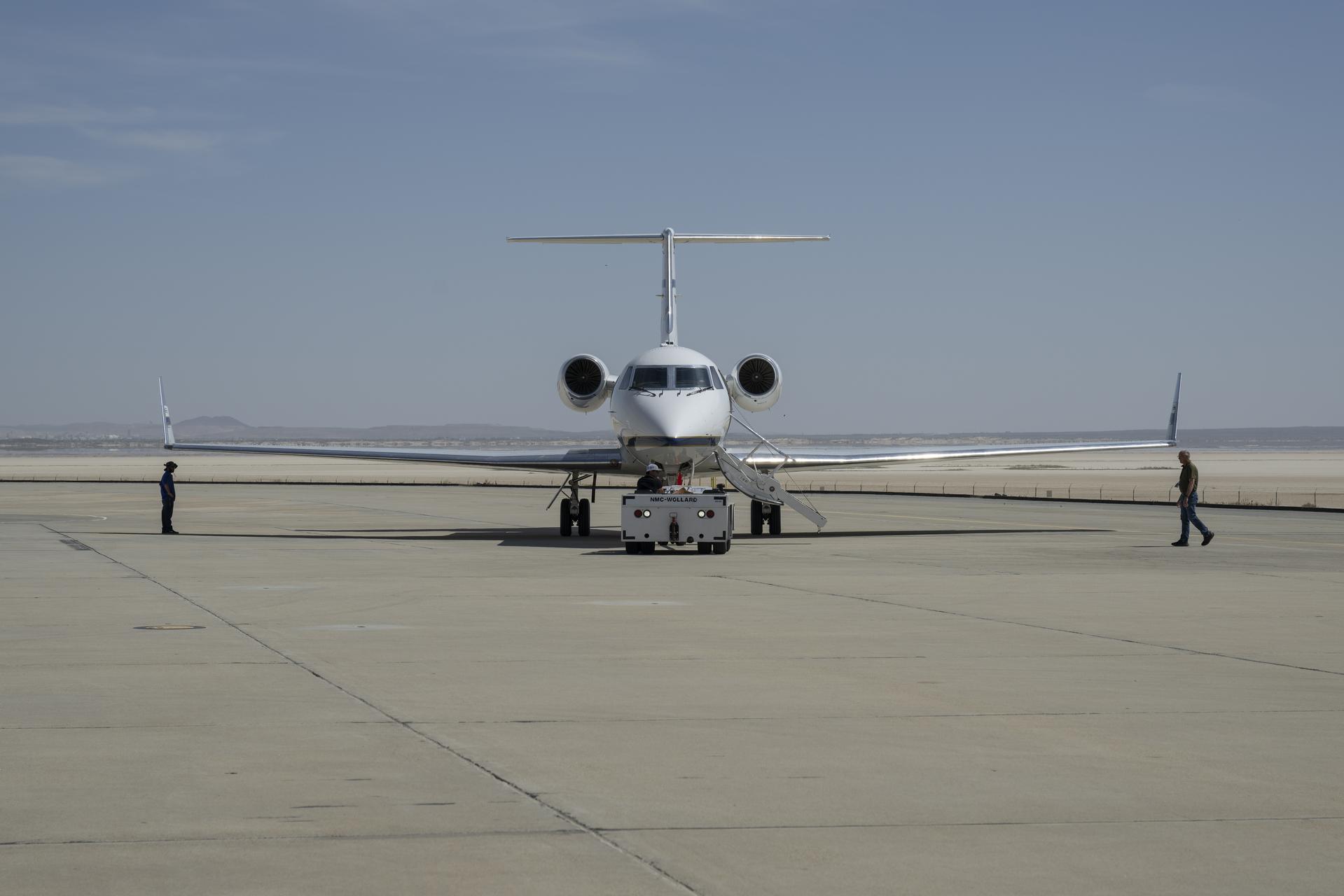 Manny Rodriguez, center, Gulfstream G-III aircraft crew chief, drives a tug while mechanic Marlon Espinoza, left, and Scott Erickson, a quality assurance inspector, prepare the aircraft for takeoff on Friday, March 27, 2026, at NASA’s Armstrong Flight Research Center in Edwards, California. The G-III will join other NASA aircraft to capture imagery of the Orion spacecraft’s heat shield during Artemis II reentry. The mission is part of NASA’s Scientifically Calibrated In-Flight Imagery (SCIFLI) project, based at NASA’s Langley Research Center in Hampton, Virginia.