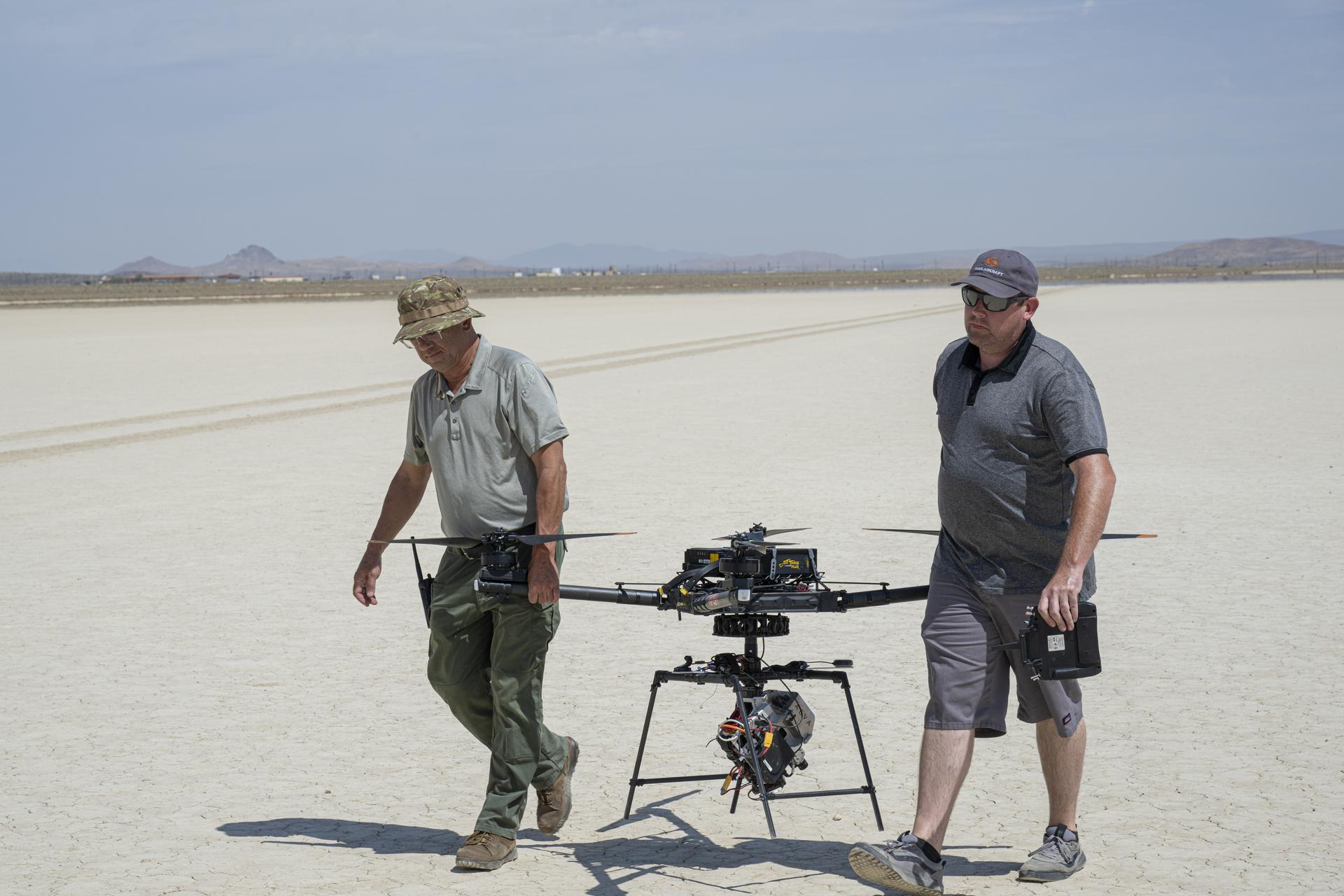 Derek Abramson, Dale Reed Subscale Flight Research Laboratory chief engineer, left, and Justin Link, small uncrewed aircraft pilot, carry NASA’s Alta-X drone near NASA’s Armstrong Flight Research Center in Edwards, California, on Thursday, Aug. 27, 2026. Researchers at NASA’s Johnson Space Center in Houston developed the advanced guidance and navigation system known as the Safe and Precise Landing – Integrated Capabilities Evolution (SPLICE) experiment, which is installed on this drone. SPLICE will help spacecraft land precisely and detect and avoid potential hazards, which is critical for NASA missions to the Moon and to Mars.