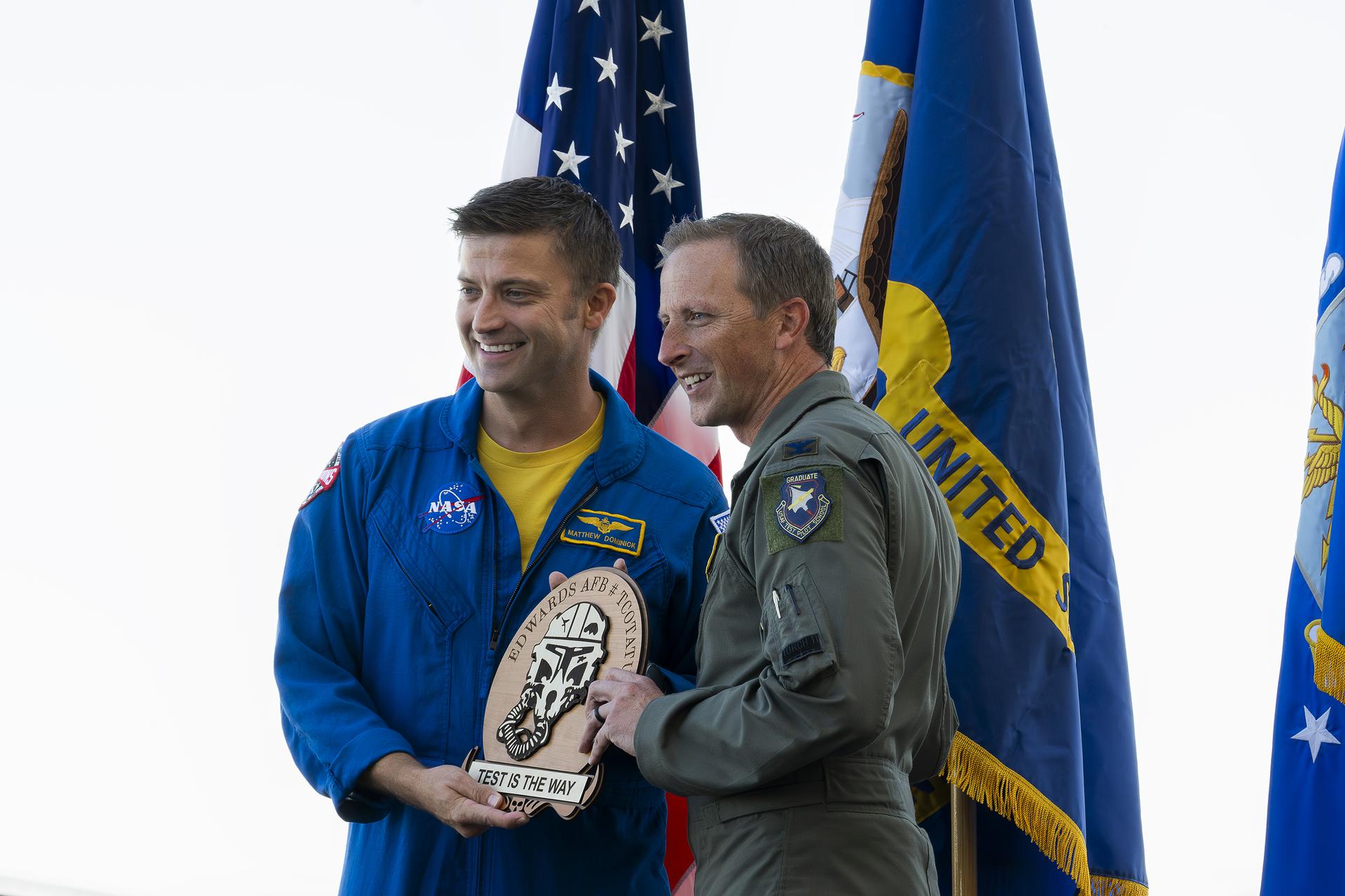 NASA astronaut Matthew Dominick receives a commemorative plaque from Col. Daniel Fredberg, Deputy Commander of the 412th Test Wing at Edwards Air Force Base, California, during Red, White, and Boom, the U.S. Air Force Test Center’s celebration of America’s 250th anniversary and NASA Armstrong’s commemoration of its 80th year on Friday, Sept. 18, 2026. The event brought together the workforce, families, and the Edwards community for a high‑energy day featuring a Flightline 5K, Ramp Fest and STEM Expo, static aircraft displays, hands‑on STEM activities, and a NASA flyover with a sonic boom.
