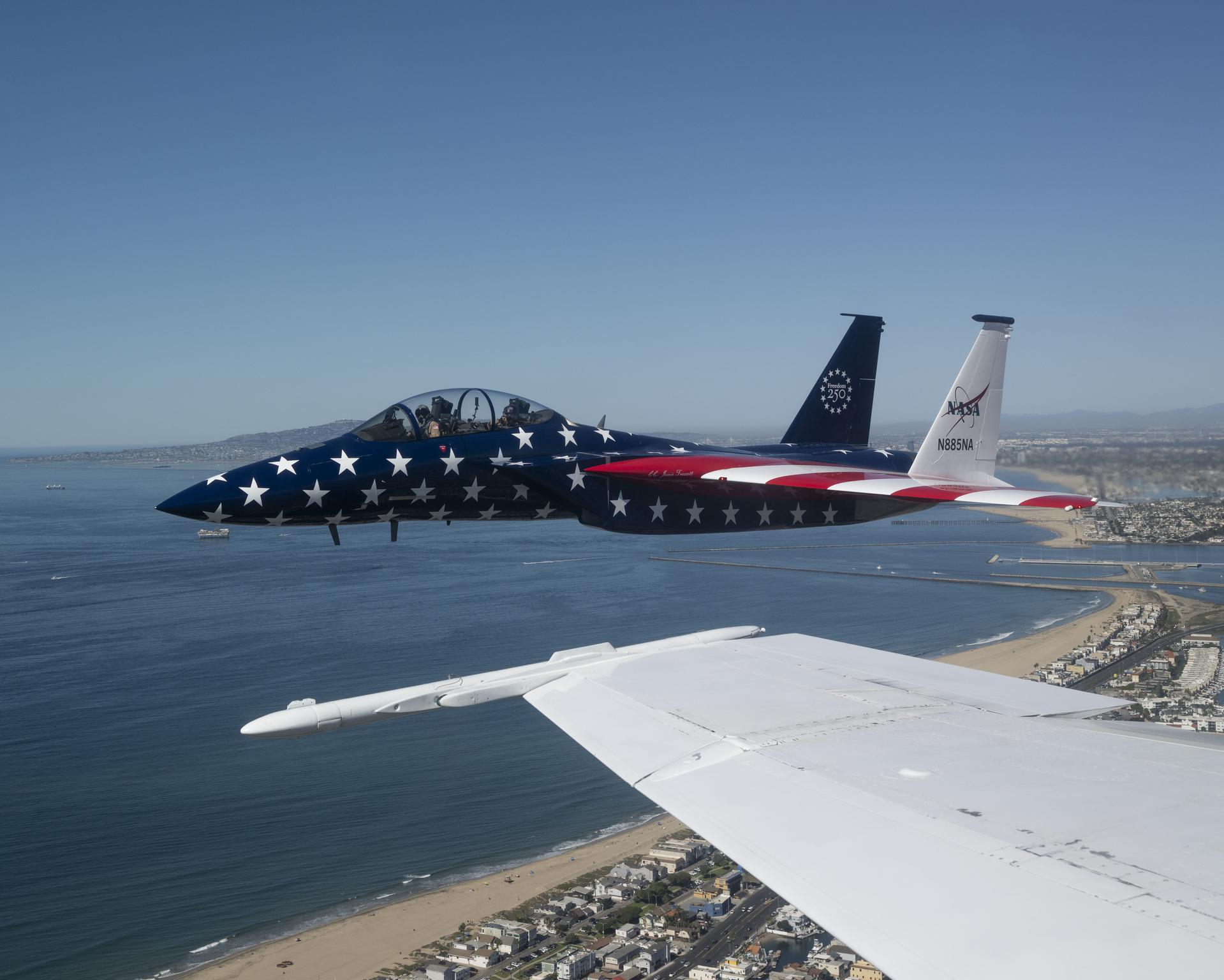 A NASA F‑15 aircraft is shown flying next to a NASA F/A‑18 during the Pacific Airshow in Huntington Beach, California, Saturday, Oct. 3, 2026. The F‑15, from NASA’s Armstrong Flight Research Center in Edwards, California, is painted in honor of America’s 250th birthday.
