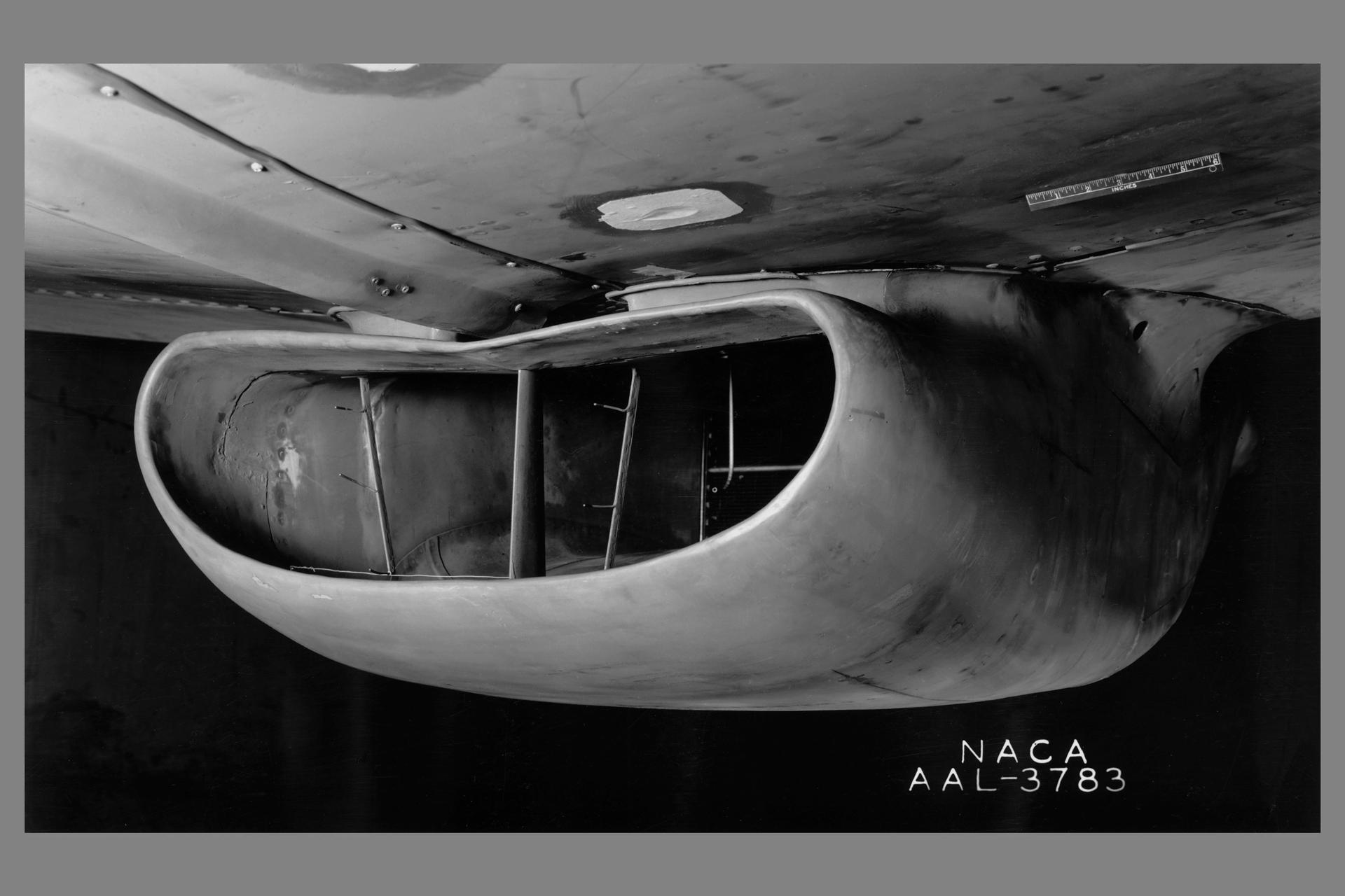 A portion of the North American P-51B airplane was tested in the 16-foot wind tunnel to devise a means of eliminating a rumble which occurred in the radiator duct system. The actual fuselage and center portion of the airplane was installed in the tunnel for this purpose as is shown.  A change in the form of the duct was made and tested, which eliminated the rumble. The entrance to the original radiator duct is indicated in this photograph, and the revised form of the duct entrance in photographer AAL-3926.