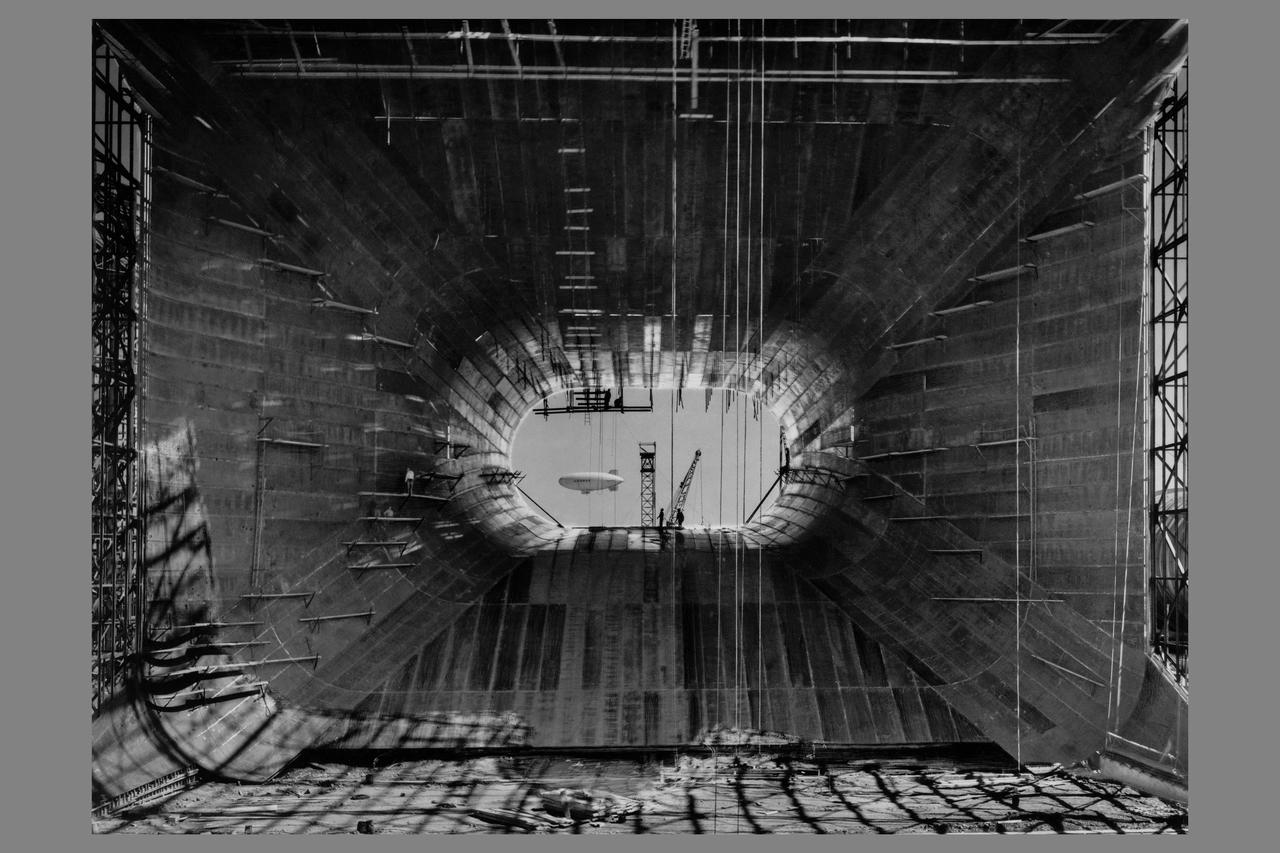 Construction of  Ames 40x80ft Subsonic Full Sscale Wind Tunnel; Approach to entrance cone looking north. Navy Blimp seen through opening.
