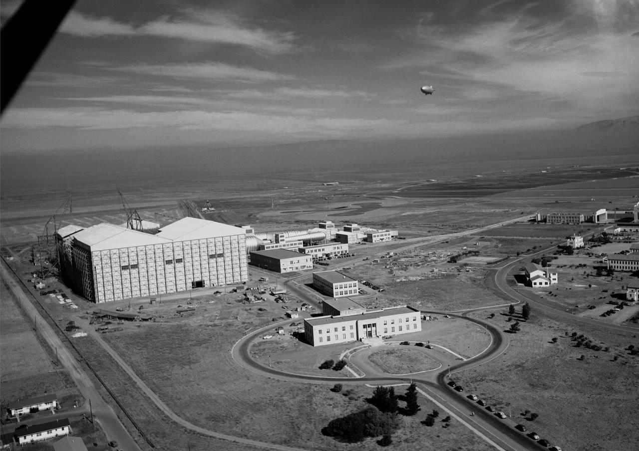 Ames aerial view of Ames Aeronautical Laboratory plot looking northeast with blimp in flight over Moffett Naval airstation.