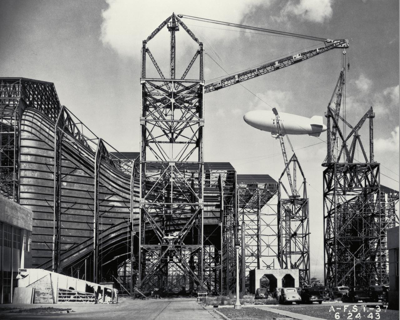 Construction of the Ames Full-Scale 40x80ft Wind tunnel. - side view of entrance cone, blimp in background